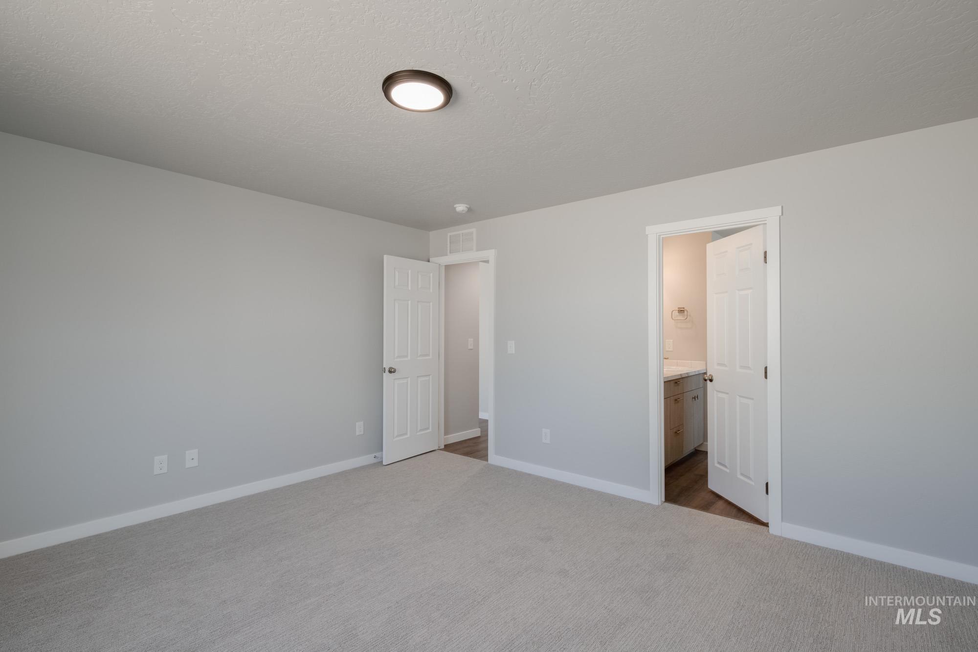 Unfurnished bedroom with carpet, a textured ceiling, and ensuite bathroom
