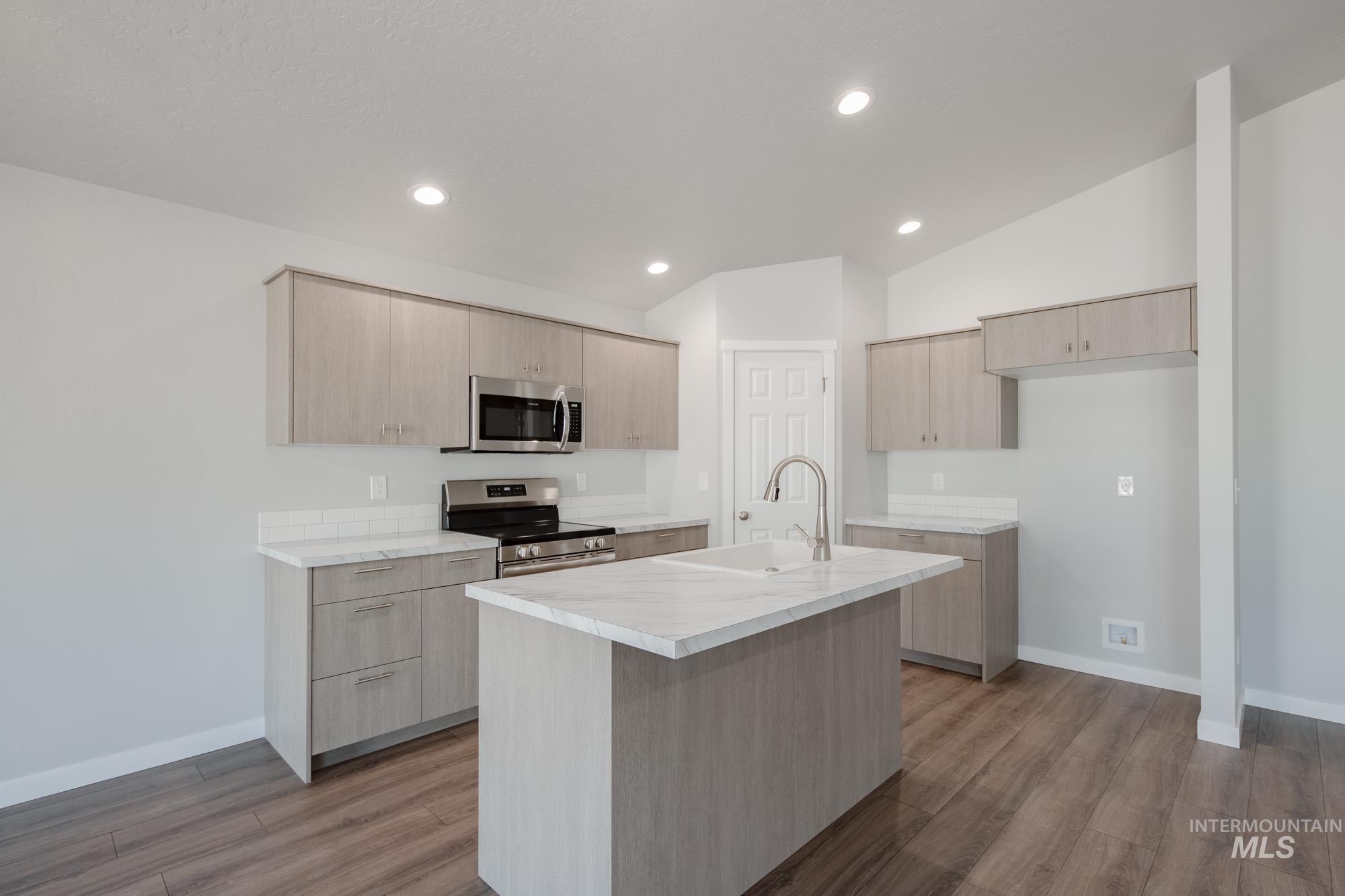 Kitchen with light brown cabinetry, appliances with stainless steel finishes, light countertops, modern cabinets, and recessed lighting