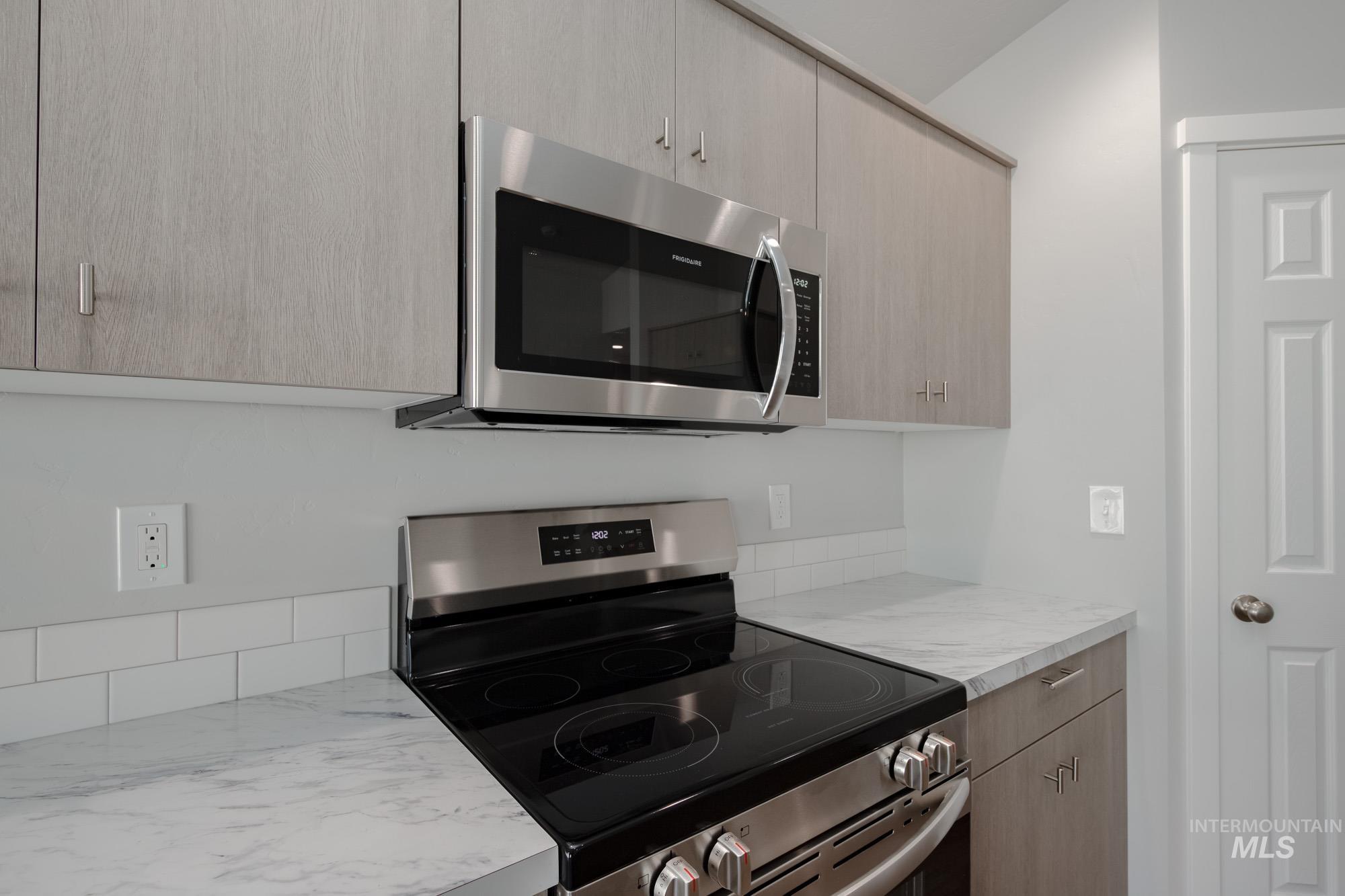 Kitchen with appliances with stainless steel finishes, light countertops, light brown cabinets, and modern cabinets