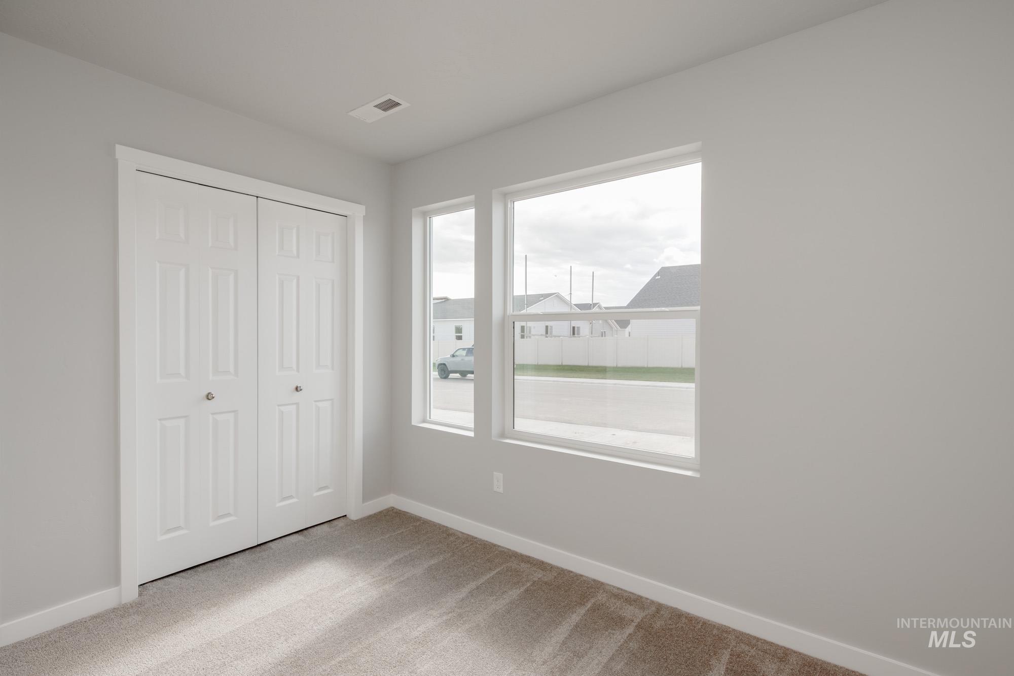 Unfurnished bedroom with light carpet and a closet