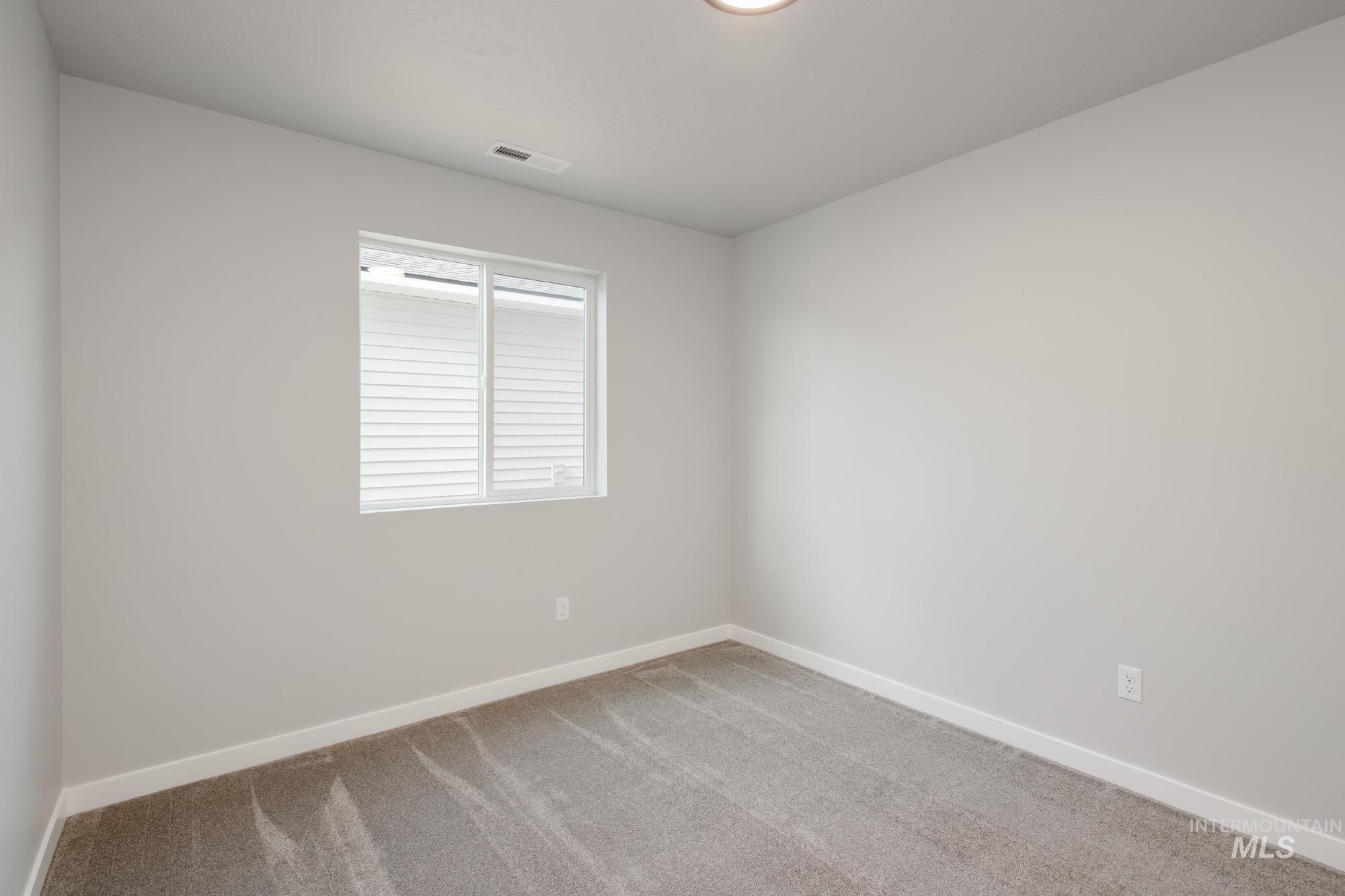 Spare room featuring carpet floors and baseboards