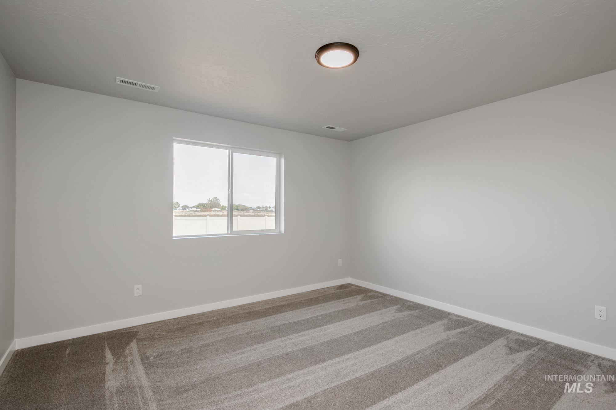Carpeted spare room featuring baseboards