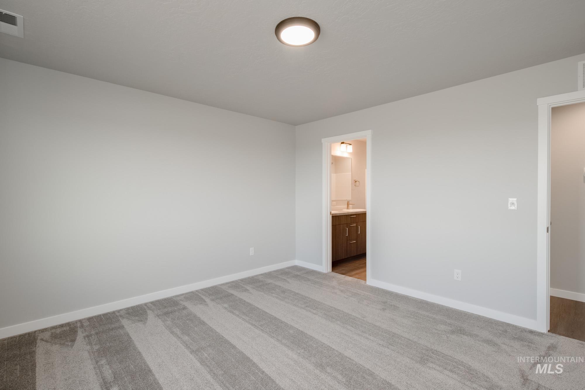 Unfurnished bedroom featuring light carpet and connected bathroom
