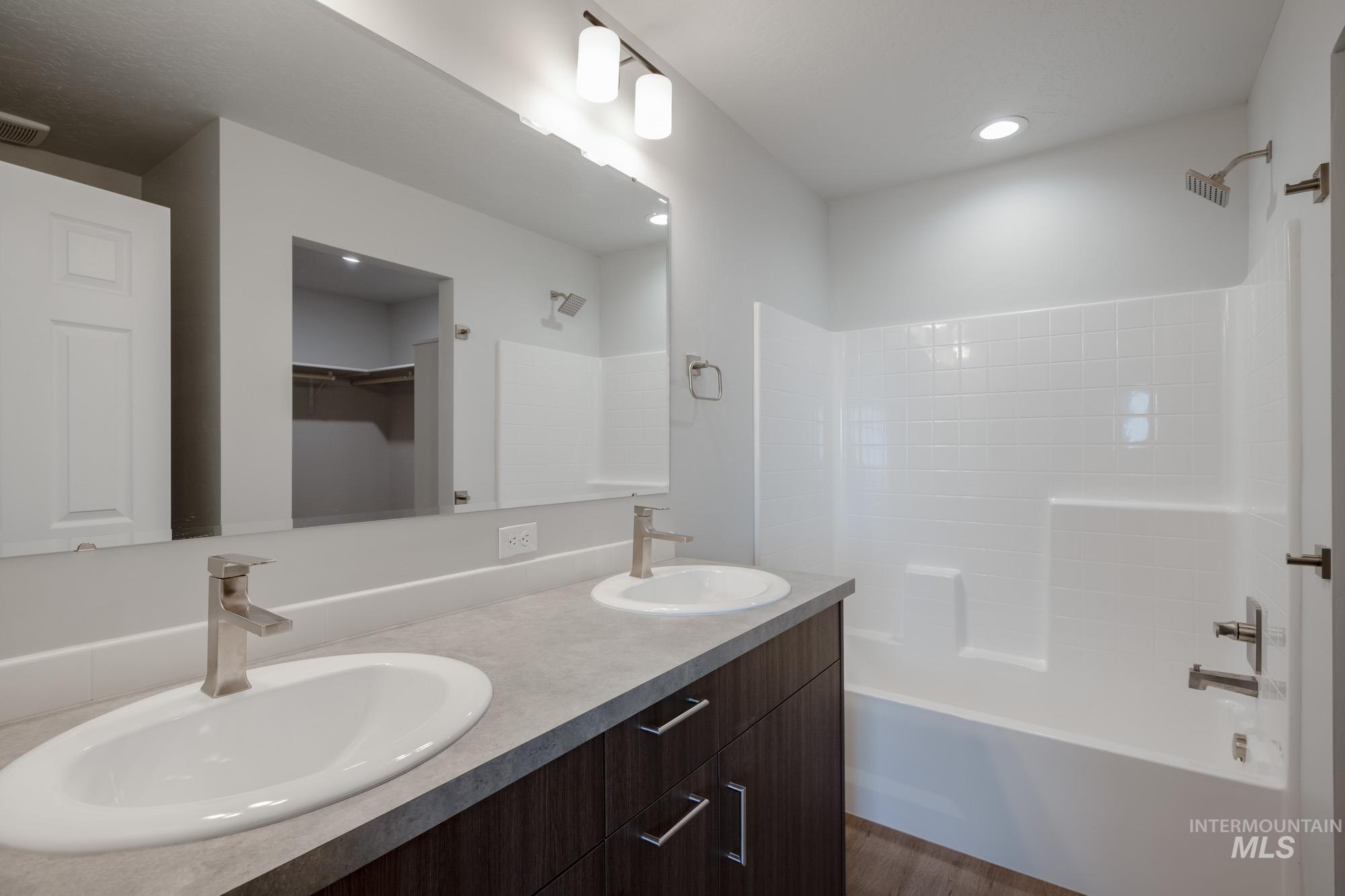 Bathroom featuring a spacious closet, double vanity, tub / shower combination, and recessed lighting