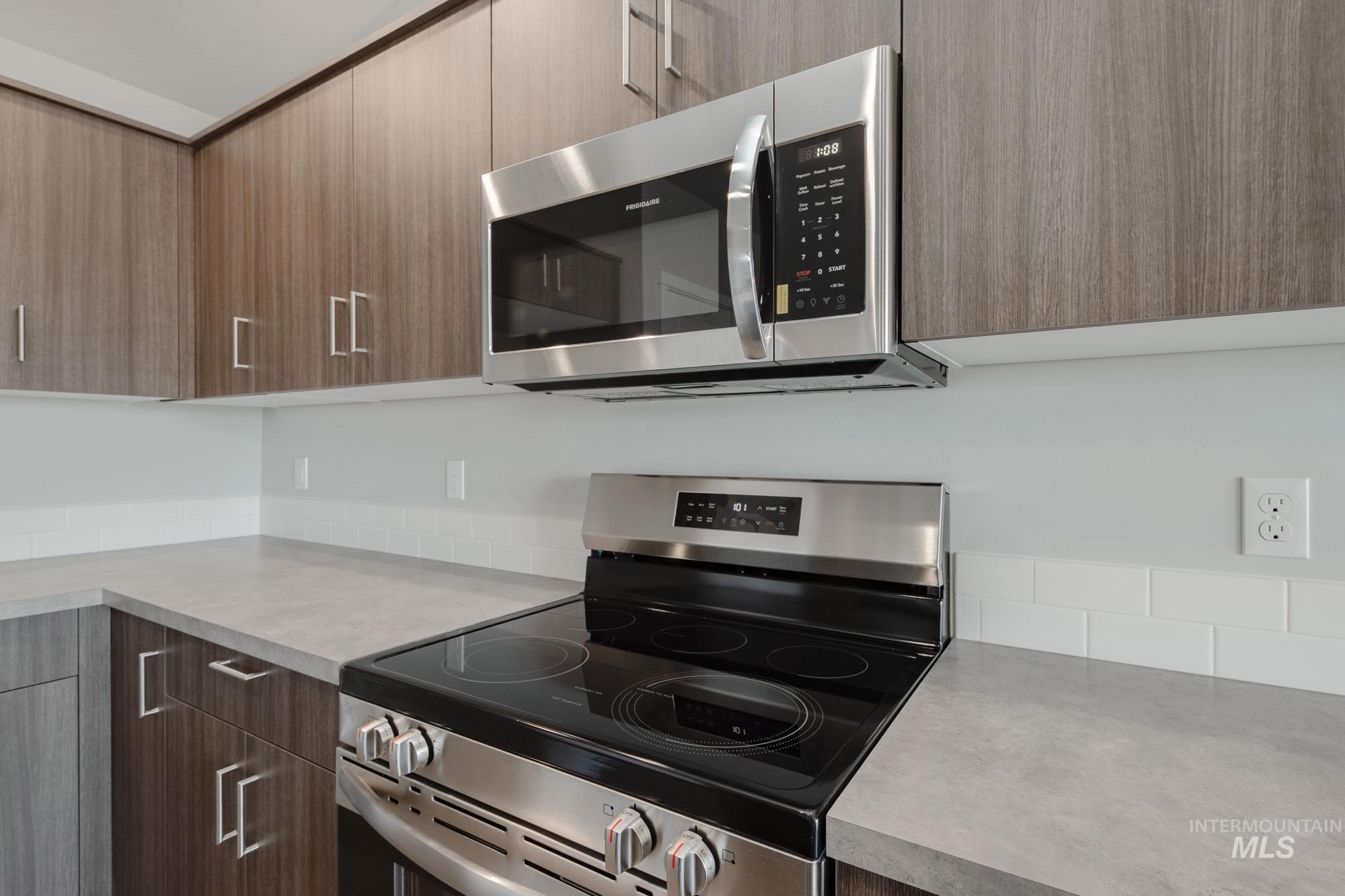 Kitchen with appliances with stainless steel finishes, modern cabinets, and light countertops