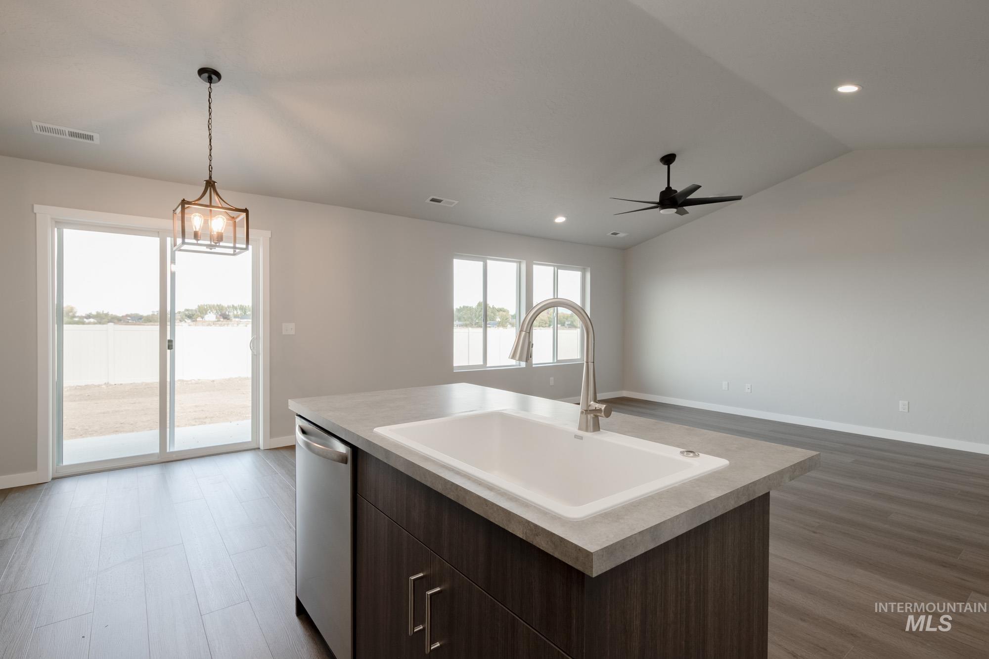 Kitchen featuring dark brown cabinetry, dark wood-style floors, open floor plan, vaulted ceiling, and dishwasher
