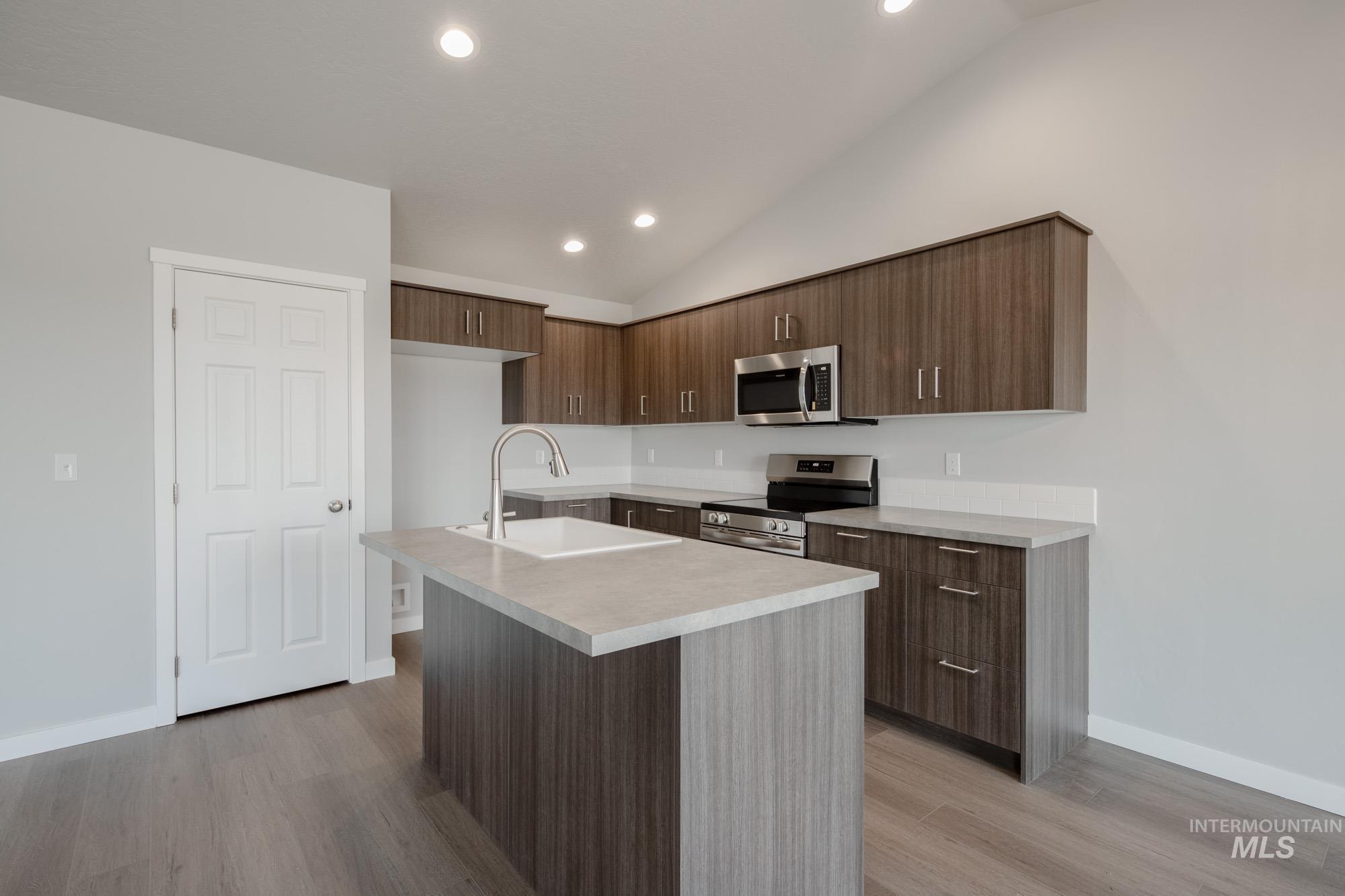 Kitchen featuring light countertops, recessed lighting, modern cabinets, appliances with stainless steel finishes, and a center island with sink