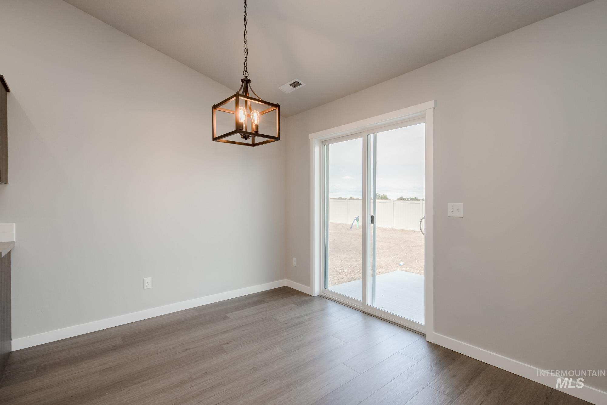 Unfurnished dining area featuring dark wood-style floors and a chandelier