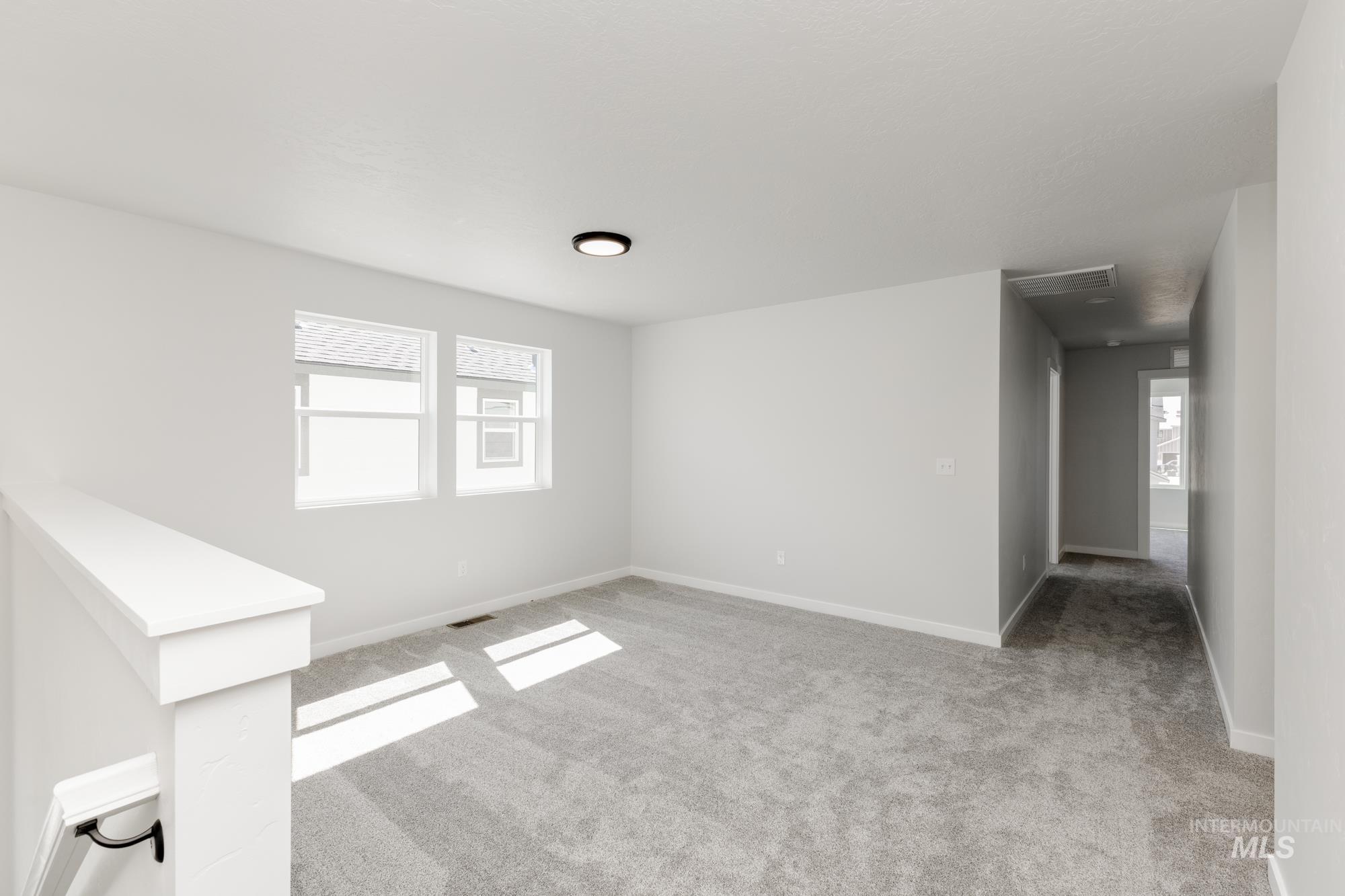 Unfurnished living room featuring light carpet and plenty of natural light
