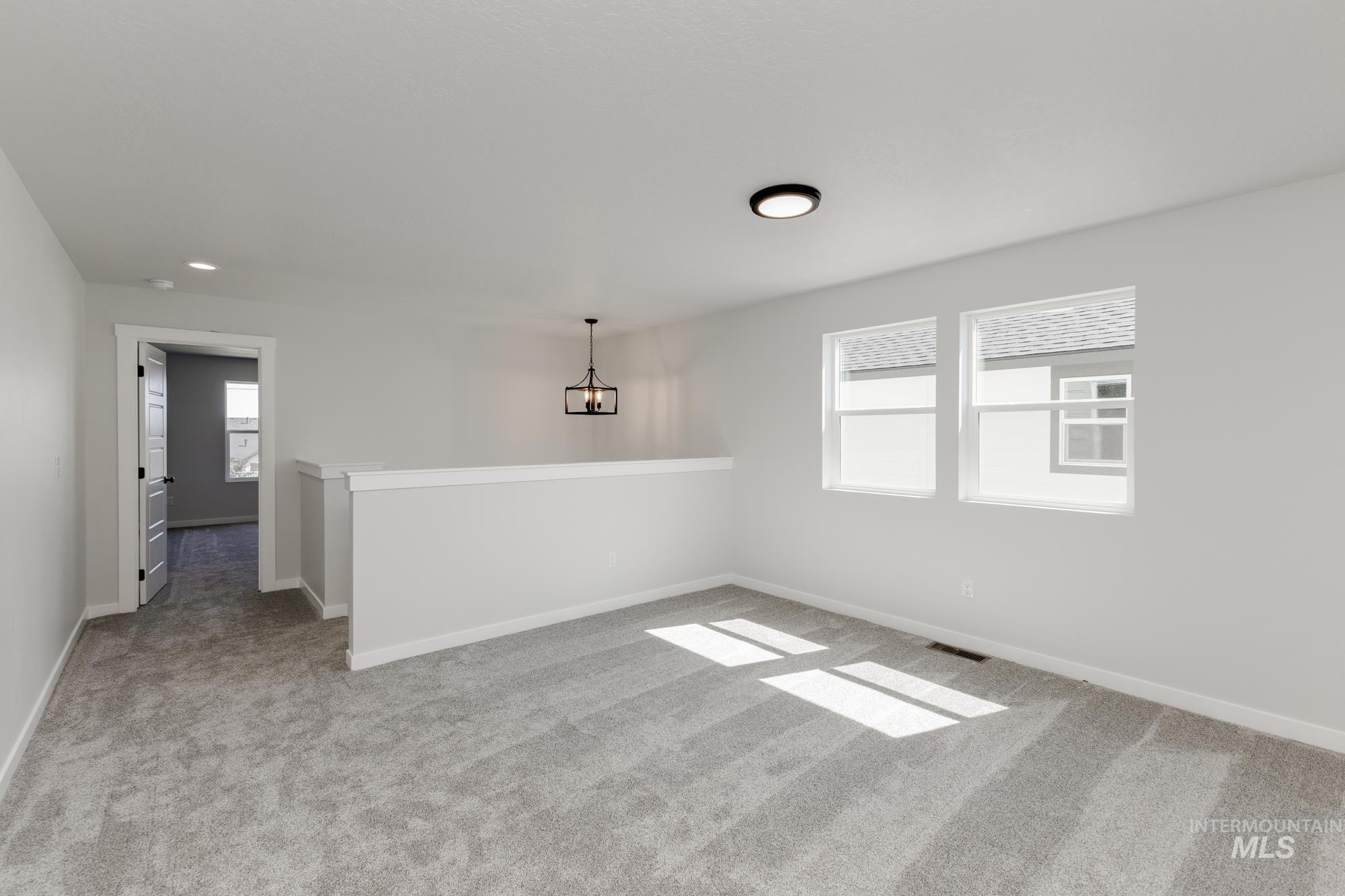 Empty room with light carpet and a chandelier