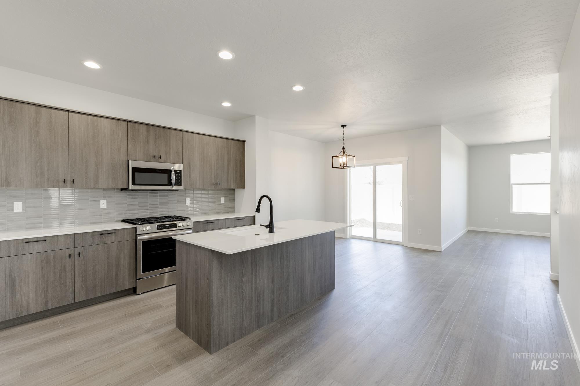 Kitchen with appliances with stainless steel finishes, backsplash, pendant lighting, recessed lighting, and modern cabinets
