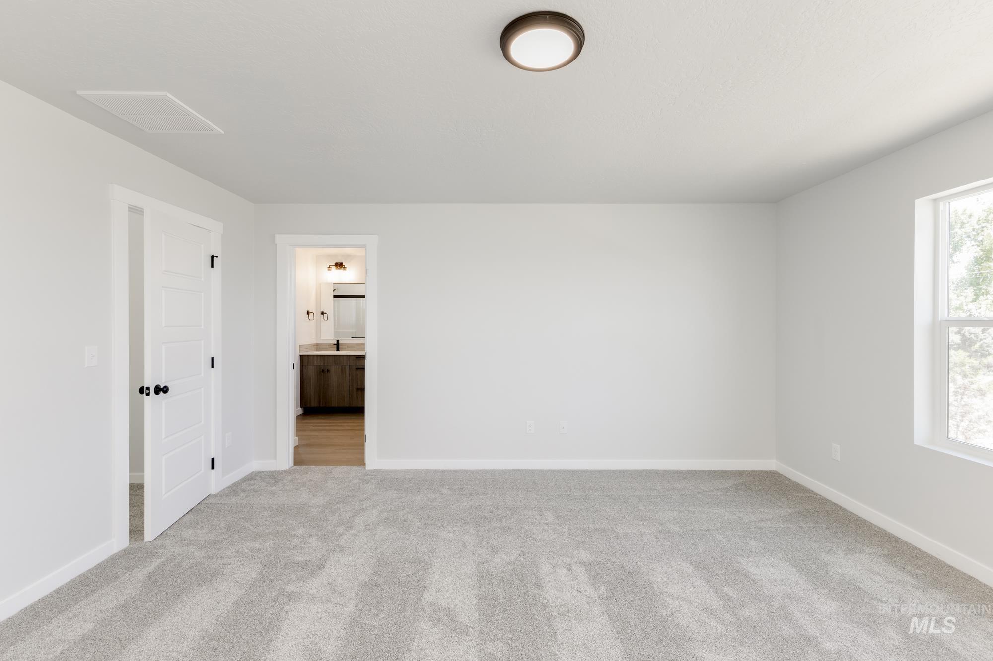 Unfurnished bedroom with light carpet and ensuite bathroom