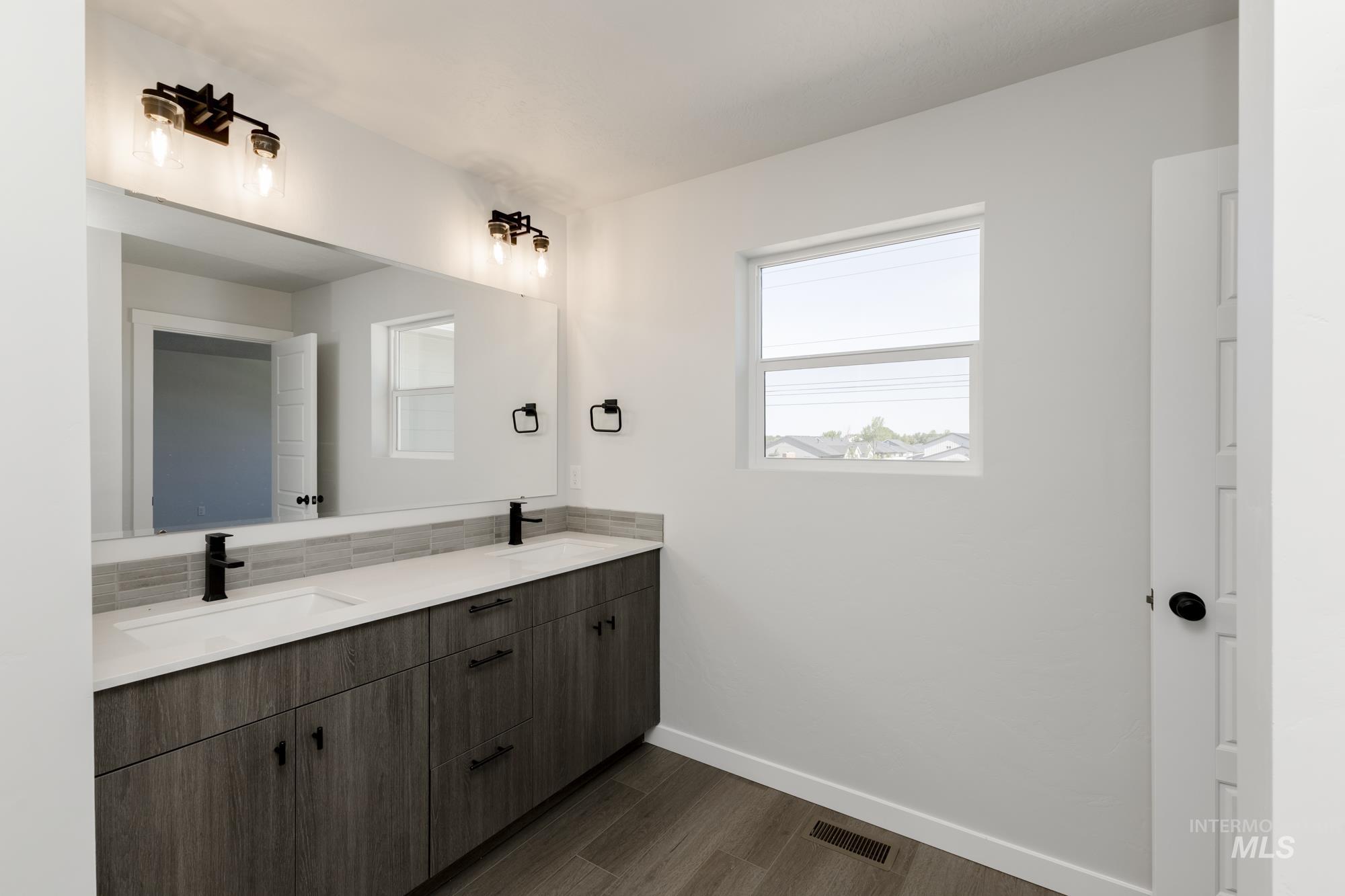 Full bathroom featuring double vanity and dark wood-type flooring