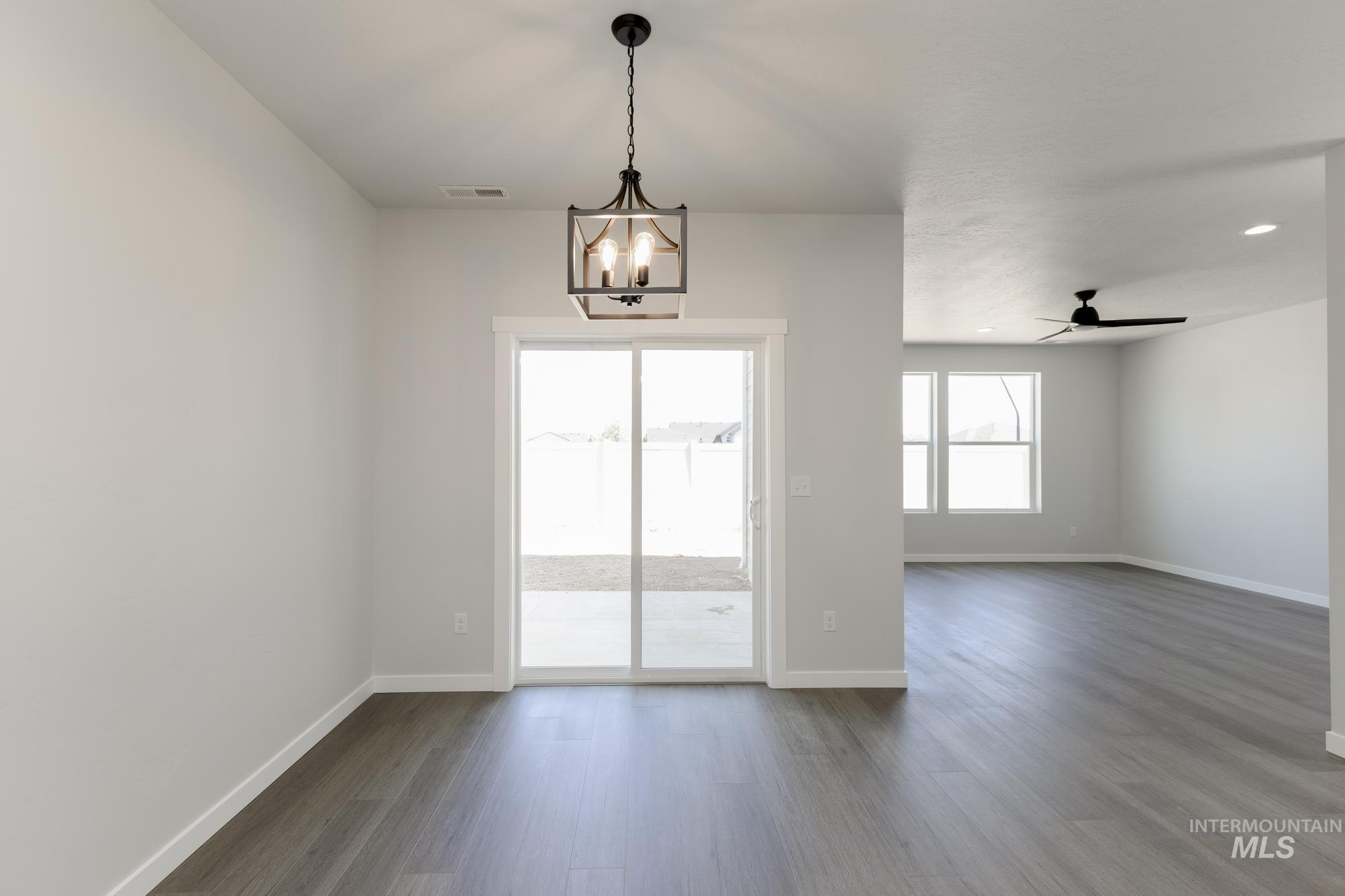 Spare room with dark wood finished floors, a ceiling fan, recessed lighting, and a chandelier