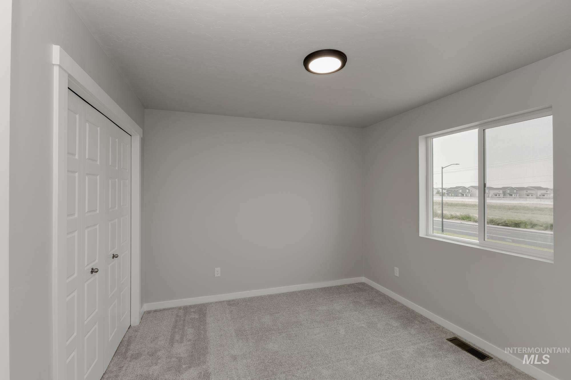 Unfurnished bedroom with light carpet and a closet