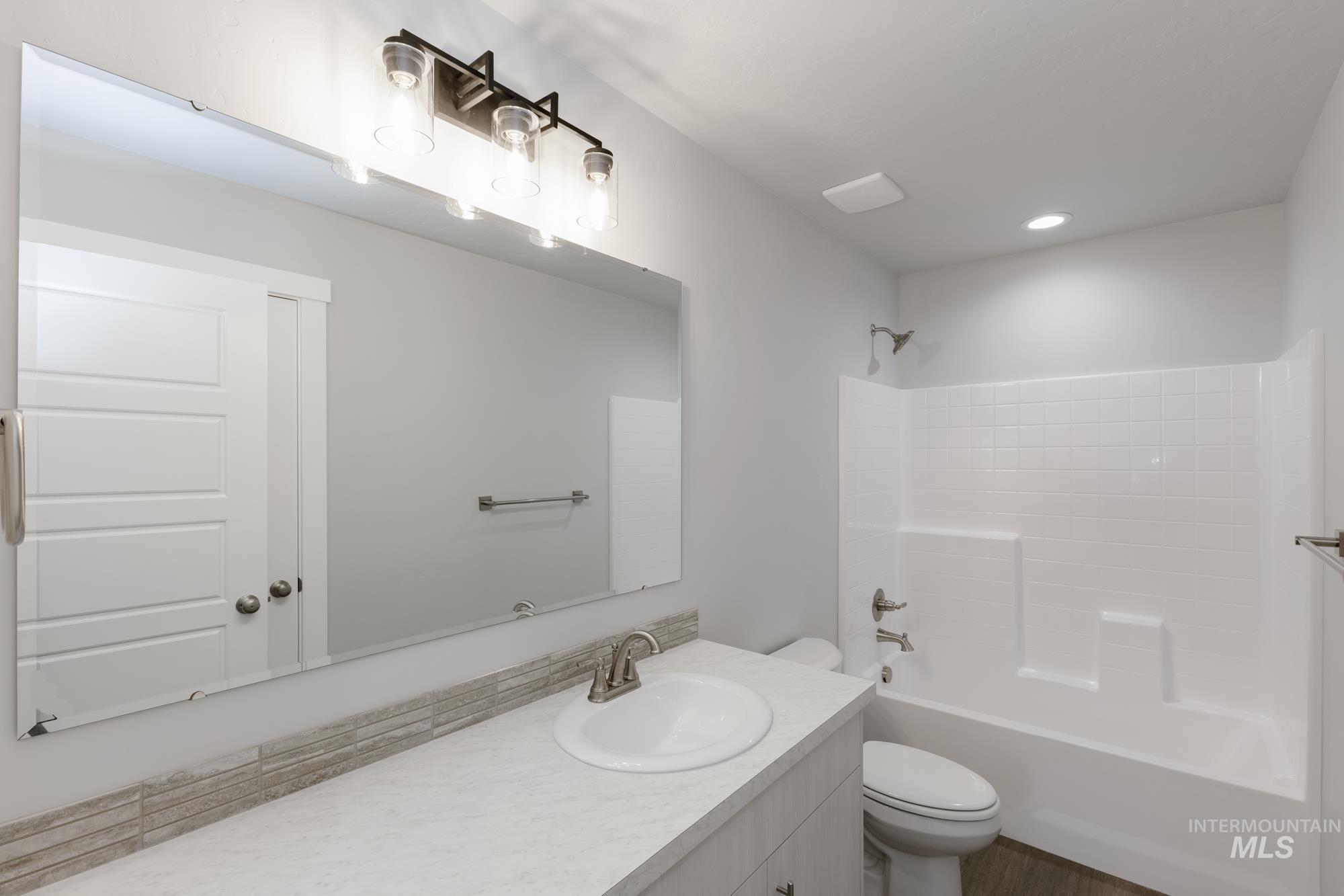 Bathroom with washtub / shower combination, vanity, and recessed lighting