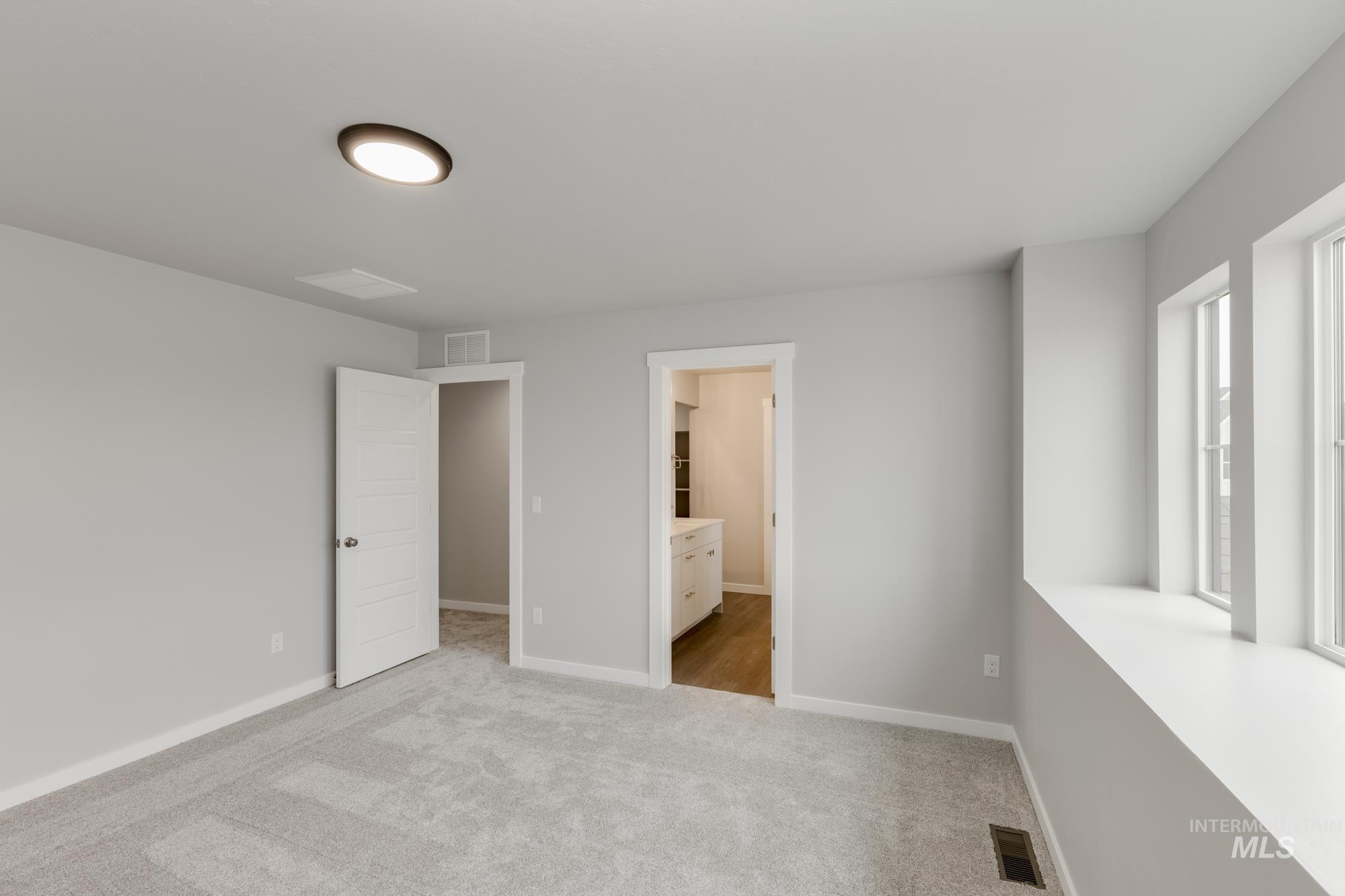 Unfurnished bedroom with light colored carpet and ensuite bathroom