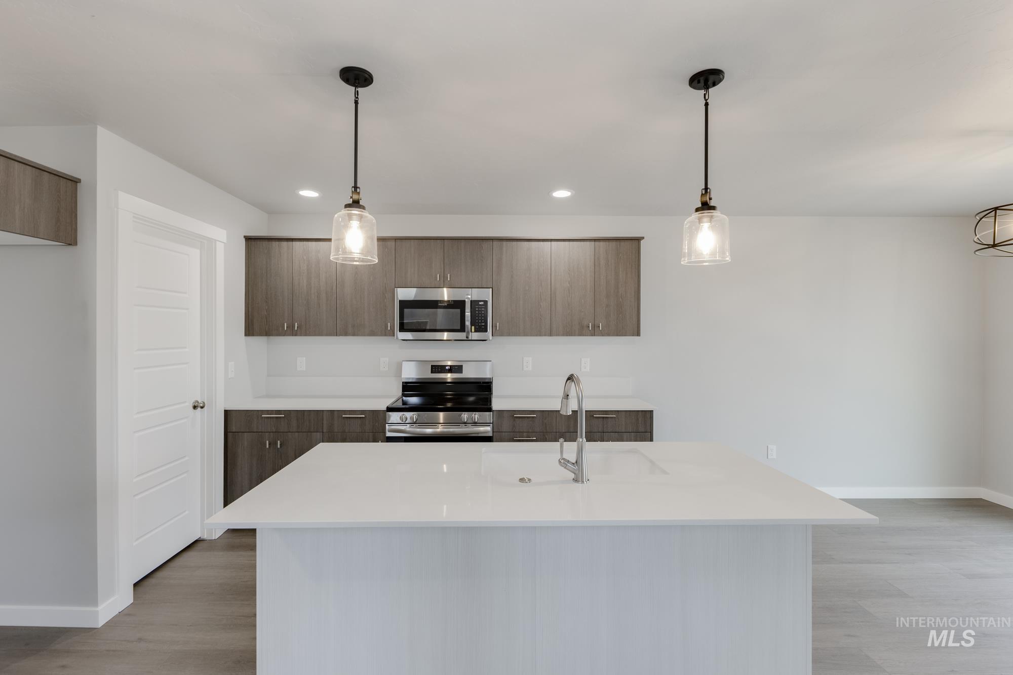 Kitchen featuring appliances with stainless steel finishes, pendant lighting, light wood finished floors, modern cabinets, and recessed lighting
