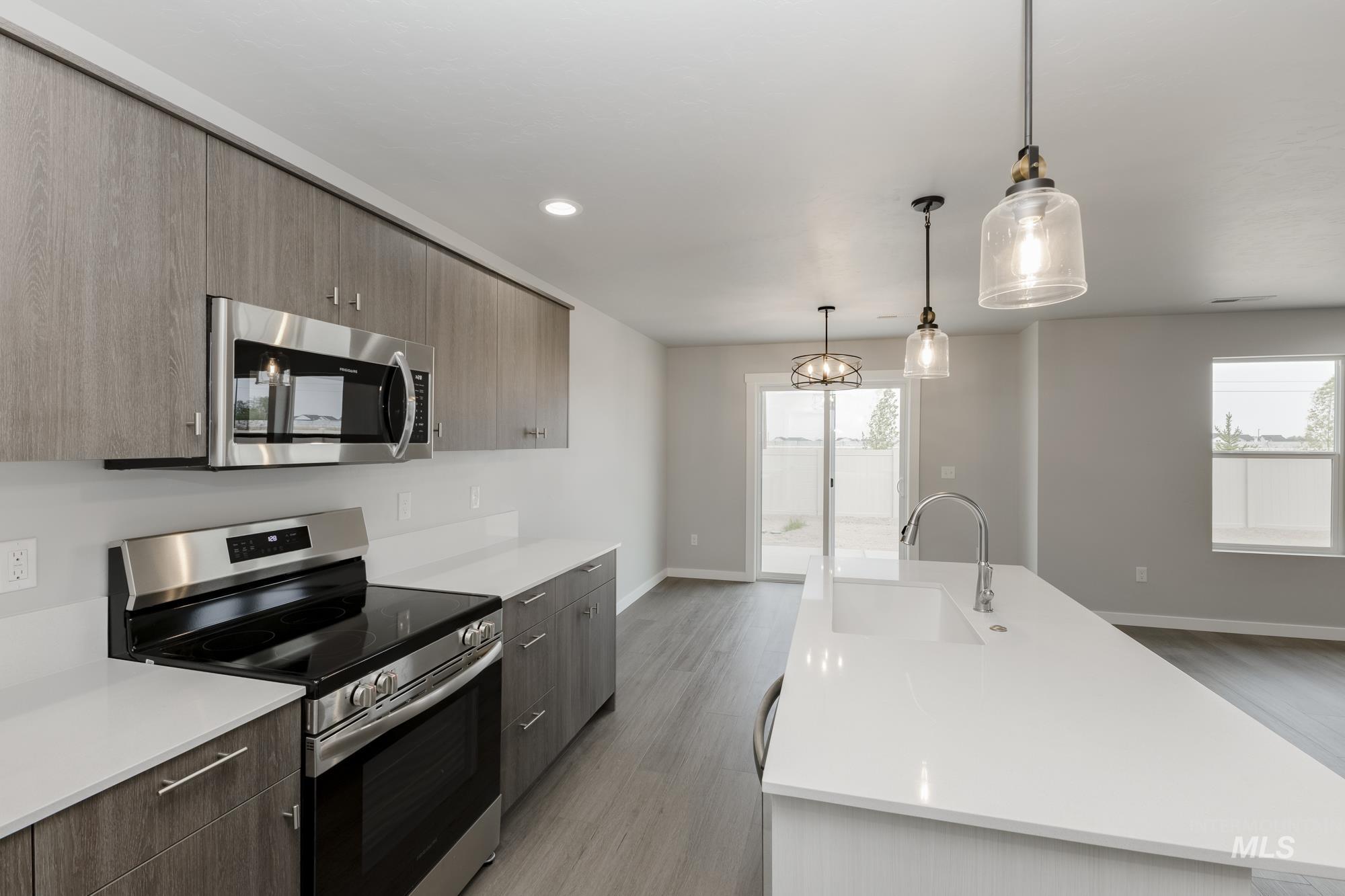 Kitchen with appliances with stainless steel finishes, hanging light fixtures, light wood-type flooring, modern cabinets, and recessed lighting