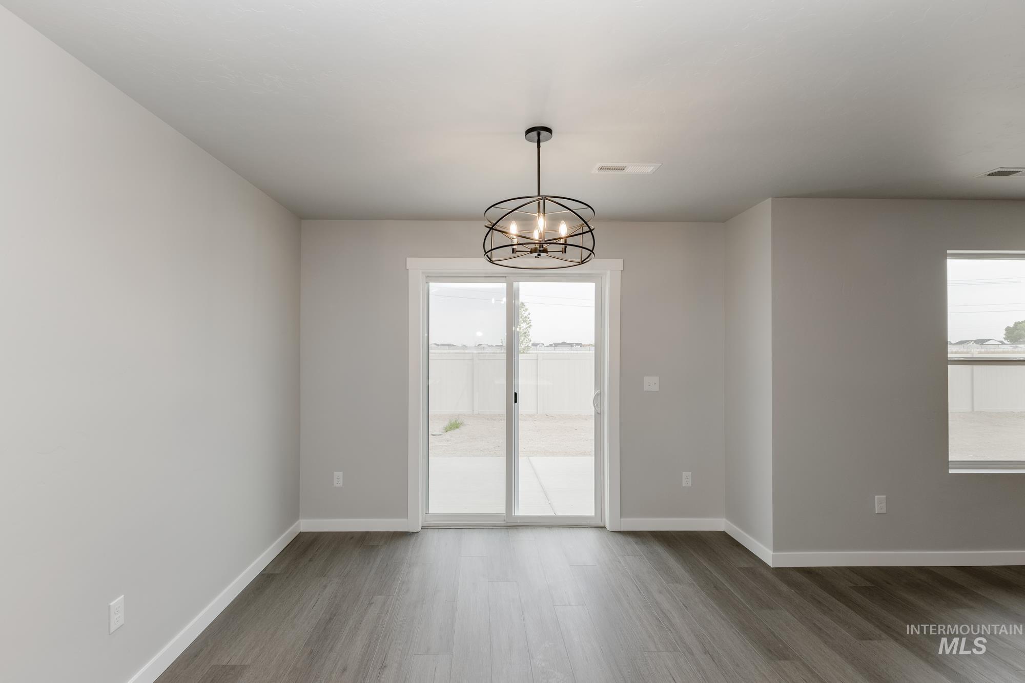Unfurnished room featuring wood finished floors and a chandelier