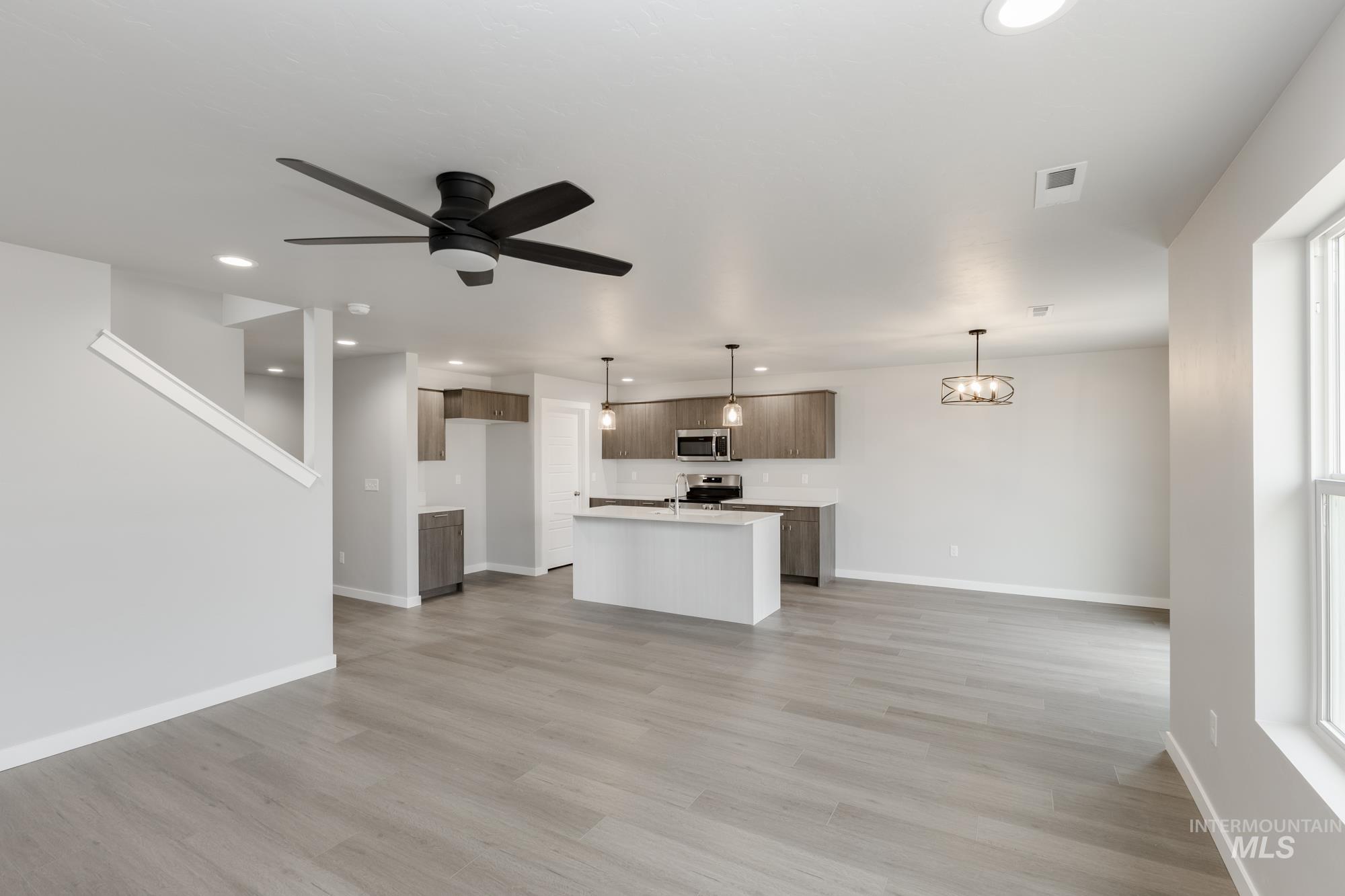 Unfurnished living room featuring recessed lighting, light wood-type flooring, a ceiling fan, and a chandelier