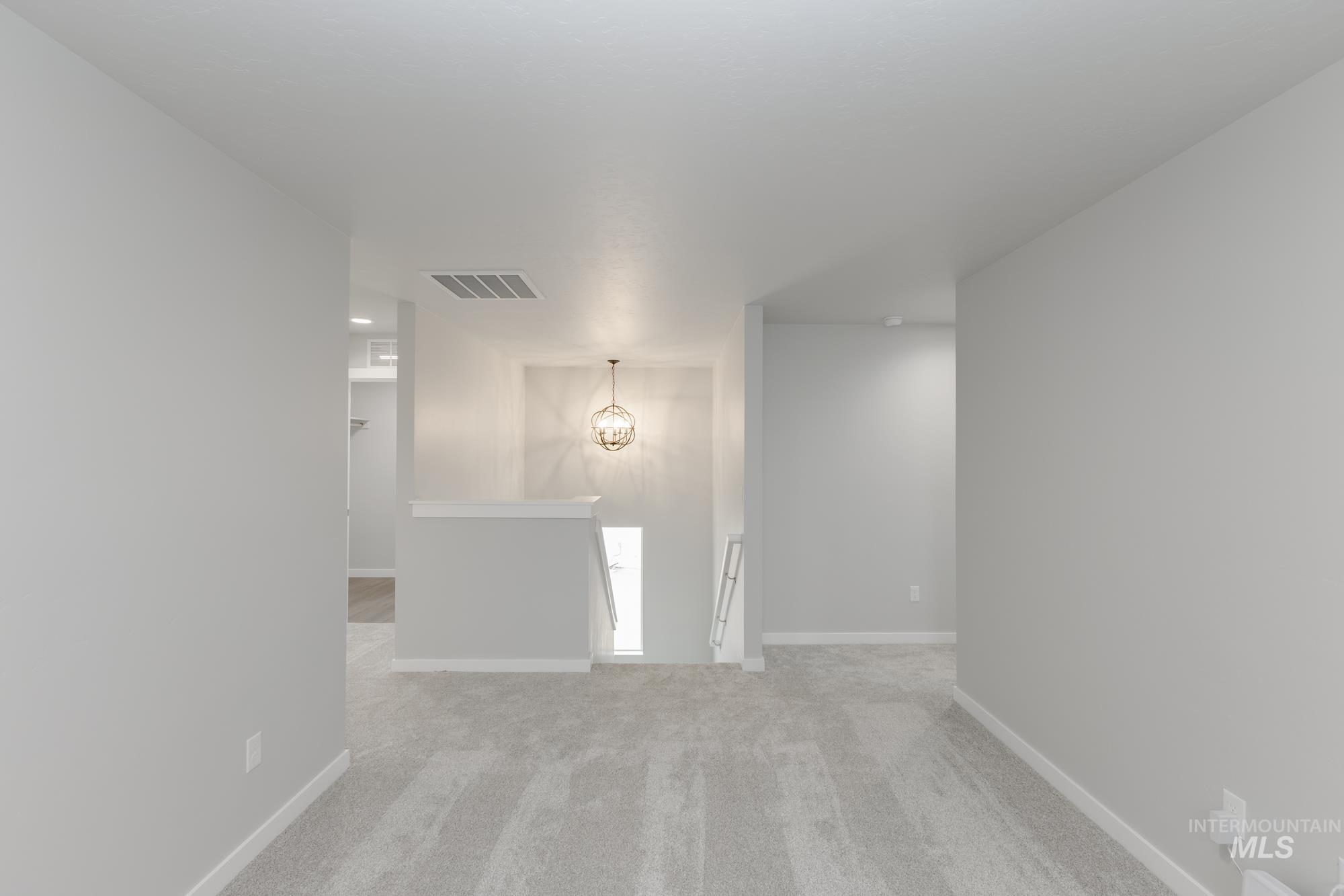 Unfurnished room with light carpet and a chandelier