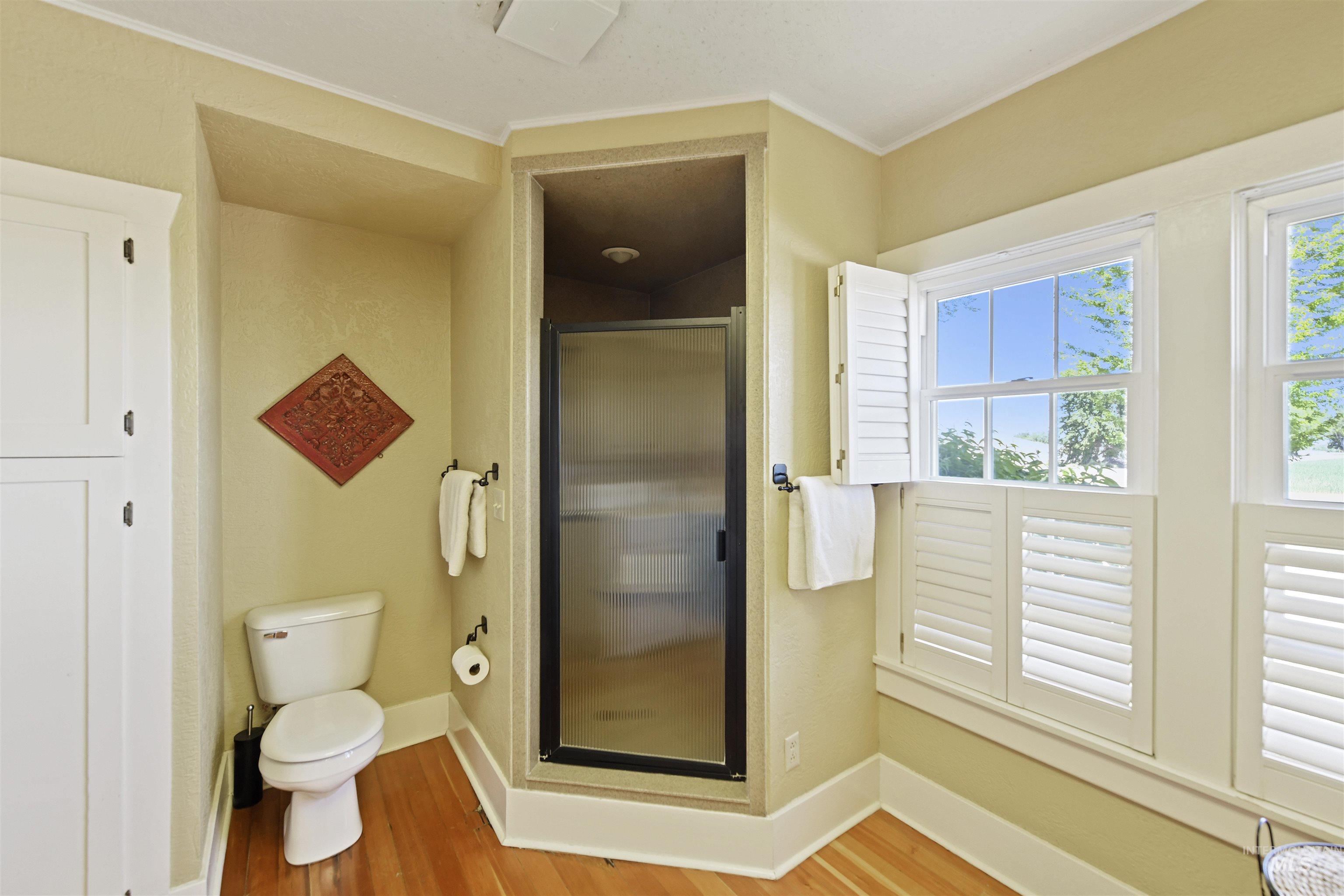 Bathroom with a stall shower, light wood-type flooring, and ornamental molding