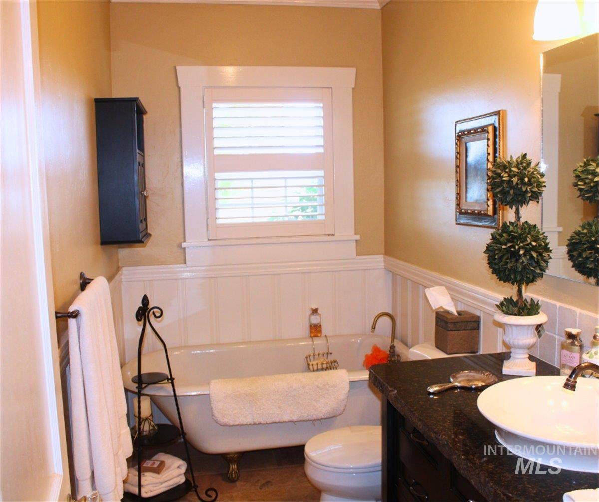 Bathroom with a freestanding bath, a wainscoted wall, and vanity