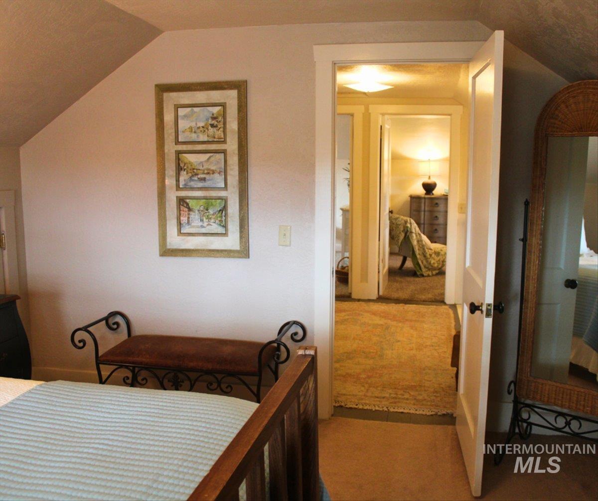Bedroom featuring light carpet and vaulted ceiling