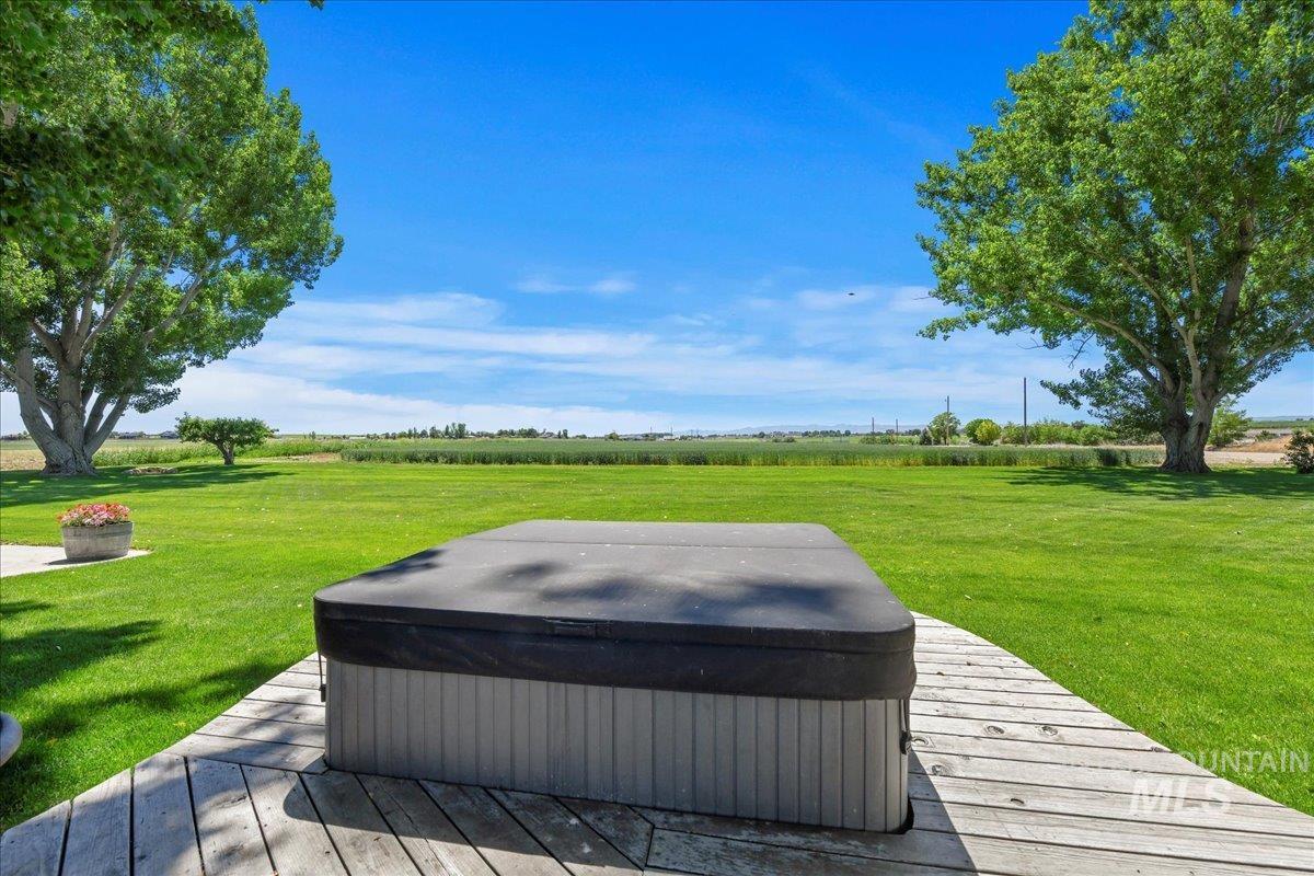 Wooden deck featuring a lawn, a view of rural / pastoral area, and a hot tub