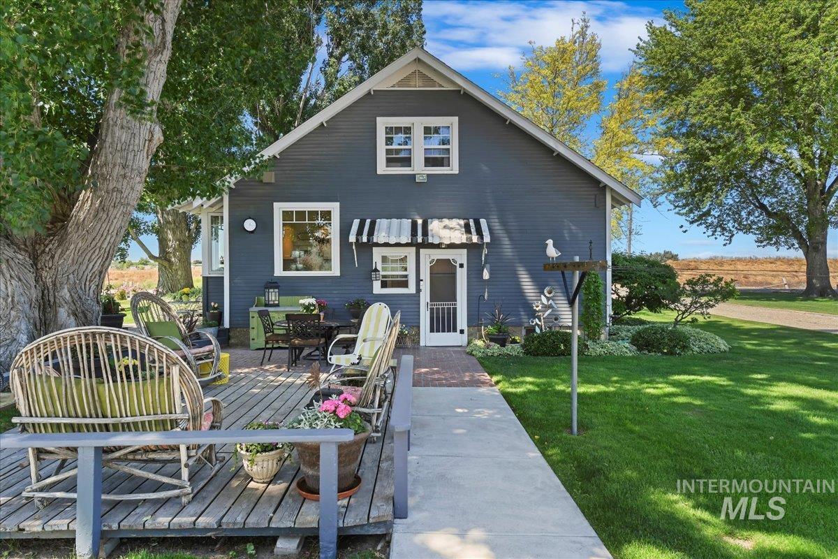 View of front of property featuring a front lawn, a deck, and outdoor dining area