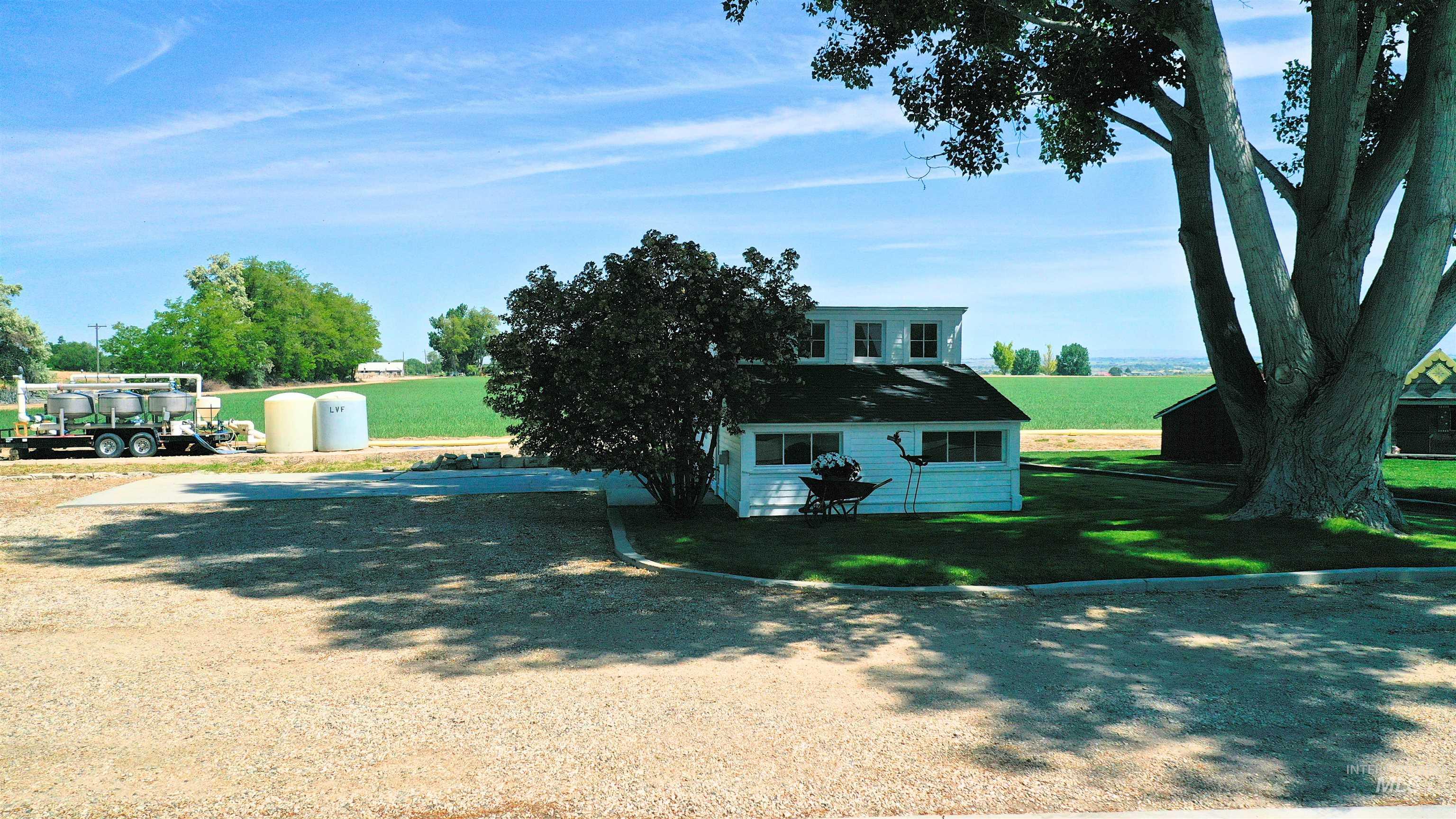 View of front of home featuring a front yard, an outdoor structure, a rural view, and driveway