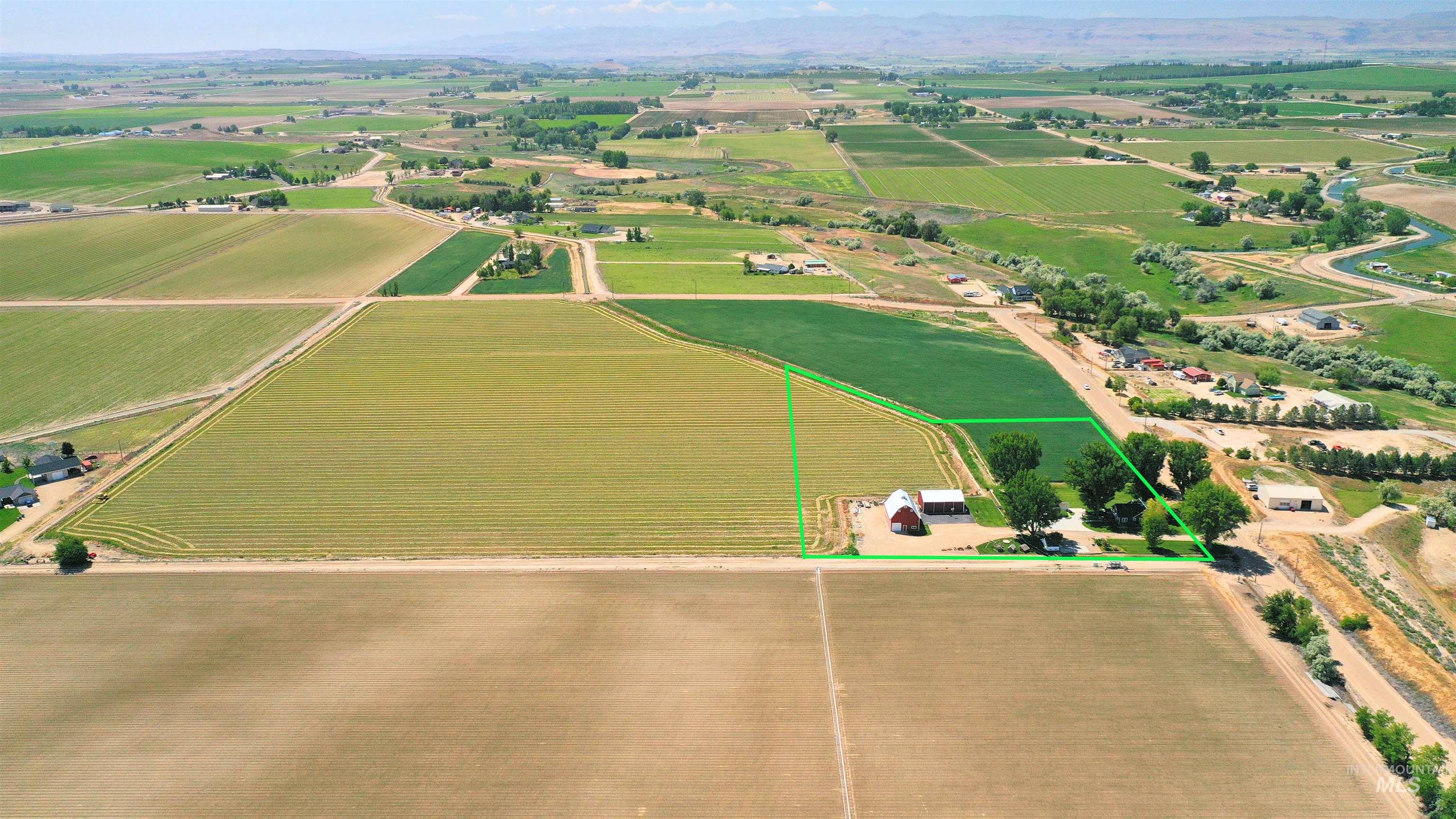 Aerial view of sparsely populated area featuring large plots for crops and property parcel outlined
