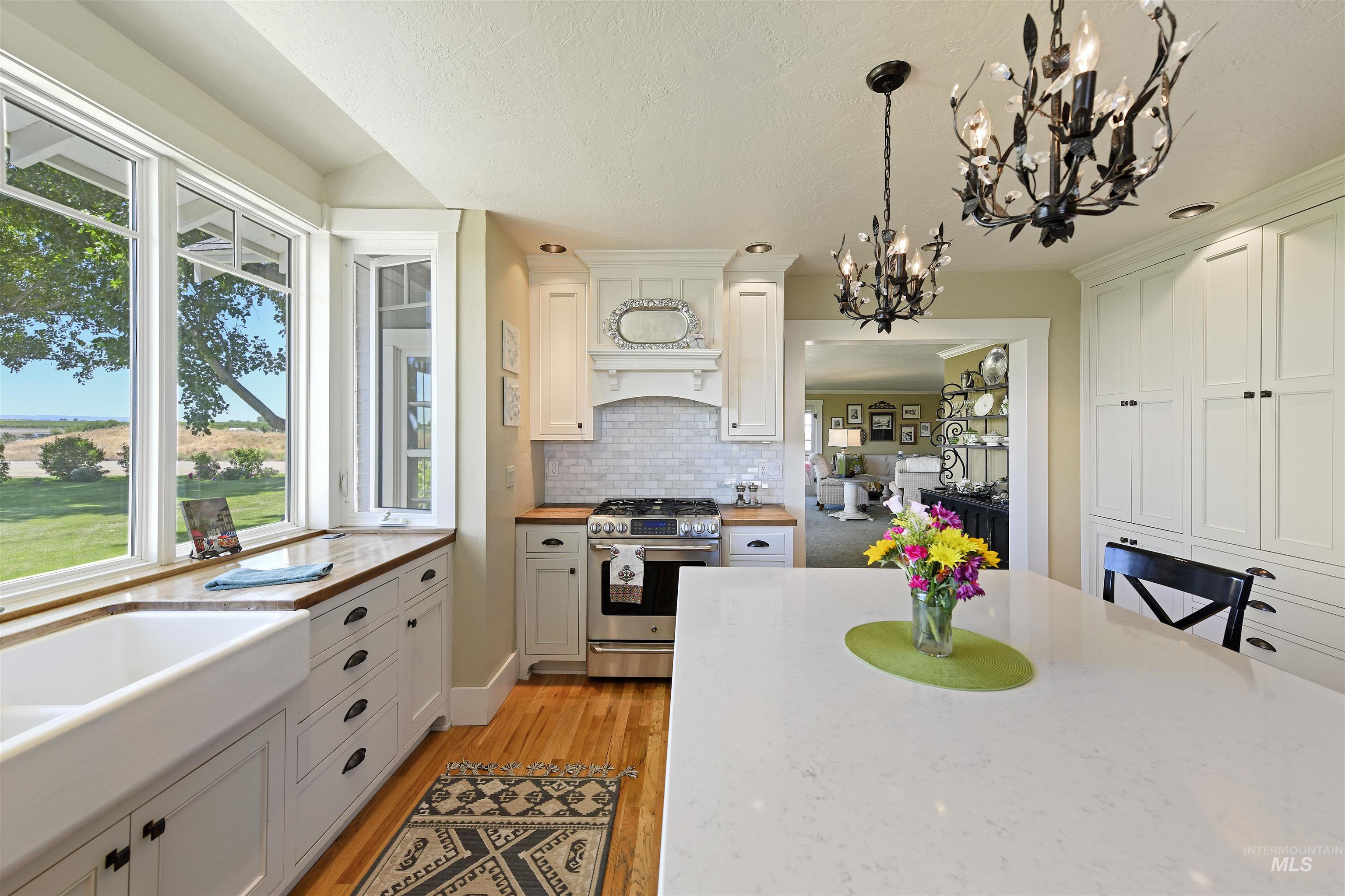 Kitchen with stainless steel gas range, decorative light fixtures, healthy amount of natural light, white cabinetry, and a textured ceiling