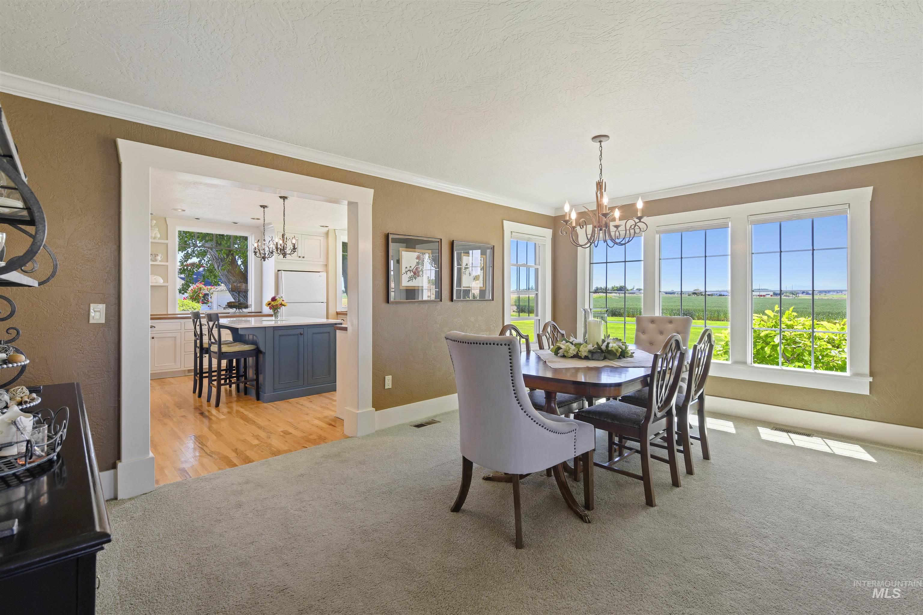 Dining space with a chandelier, crown molding, light carpet, and a textured ceiling