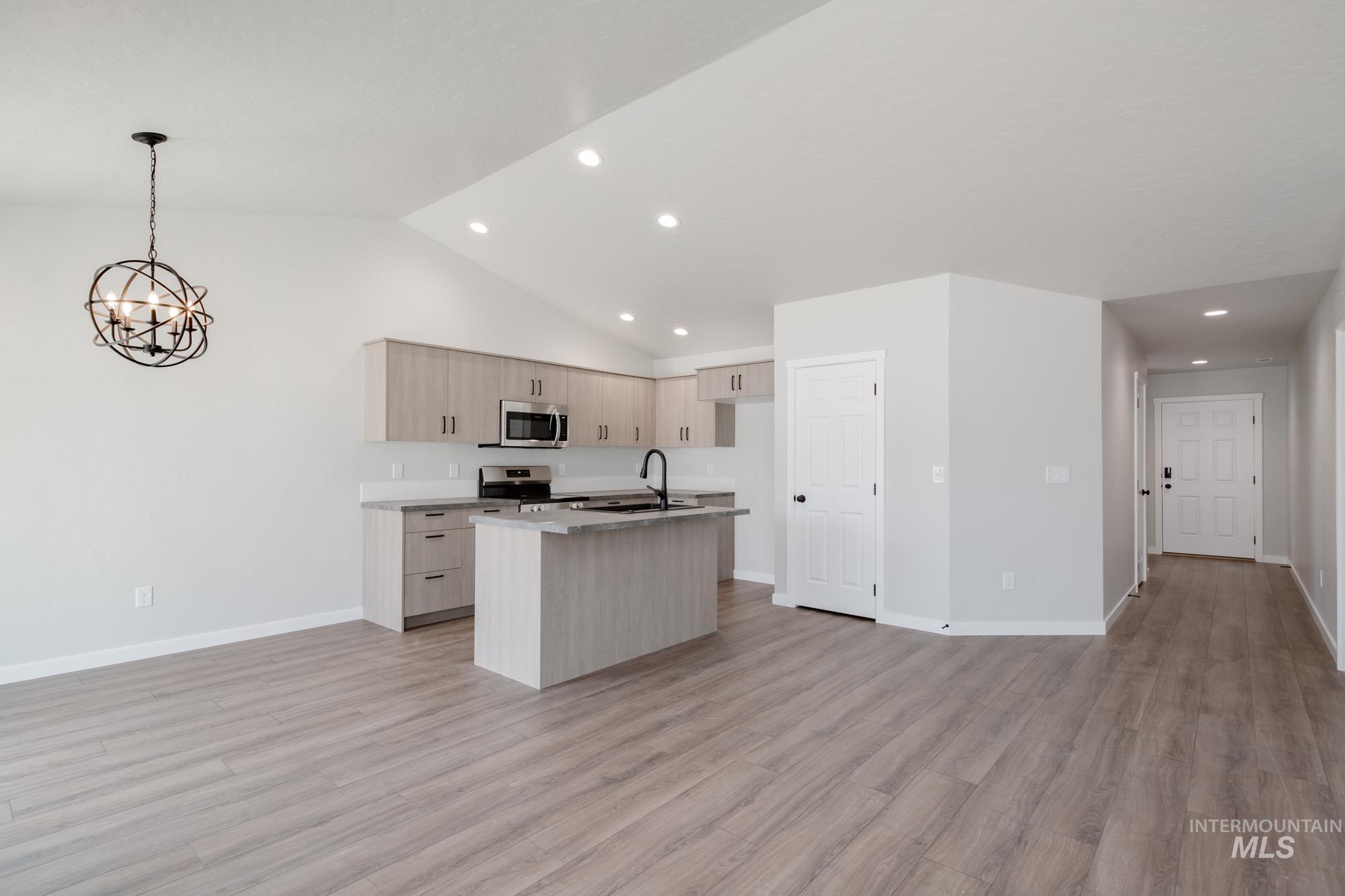 Kitchen with open floor plan, a kitchen island with sink, light wood finished floors, a chandelier, and recessed lighting