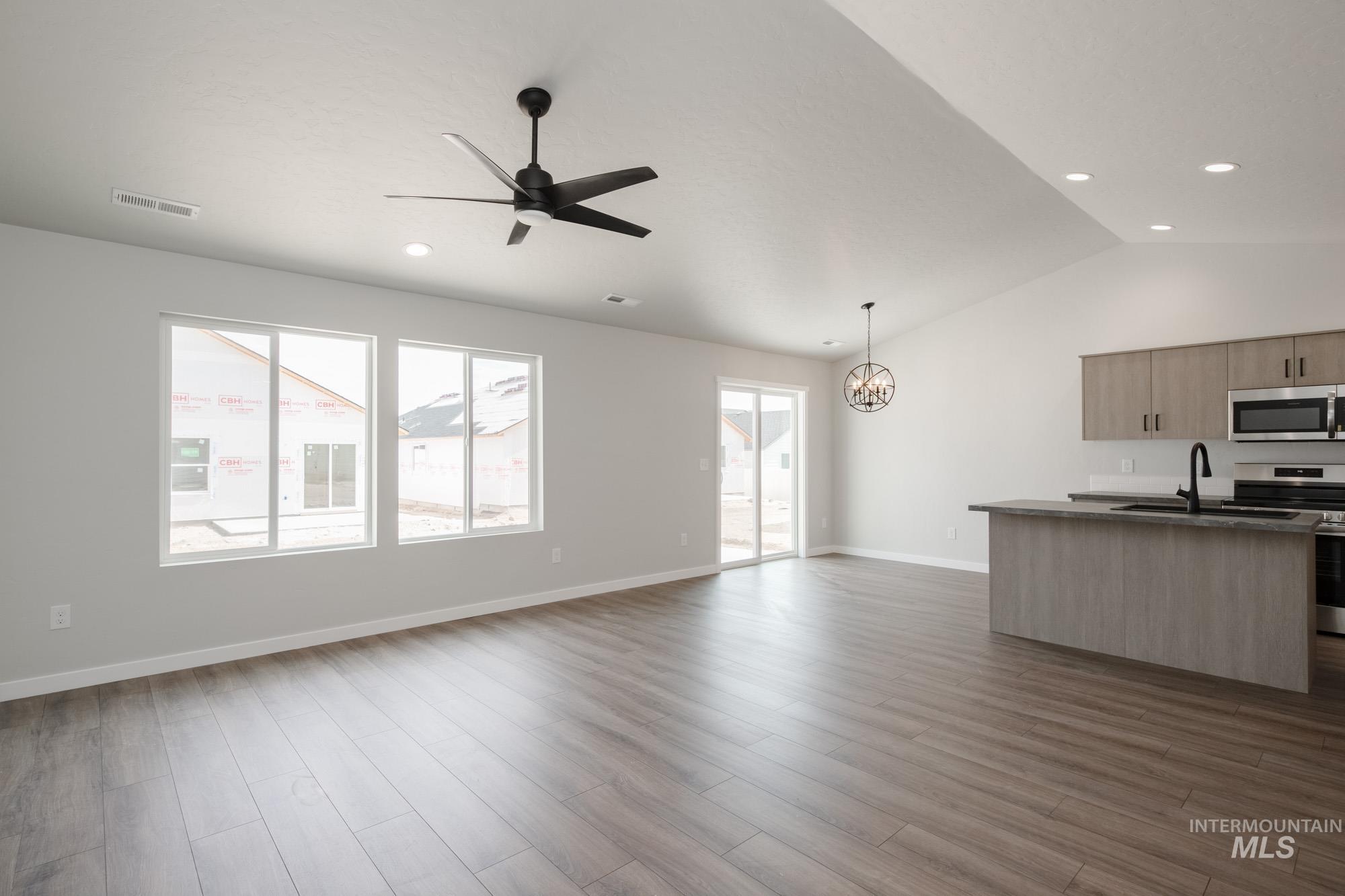 Kitchen with open floor plan, stainless steel appliances, a chandelier, ceiling fan, and light wood-style floors