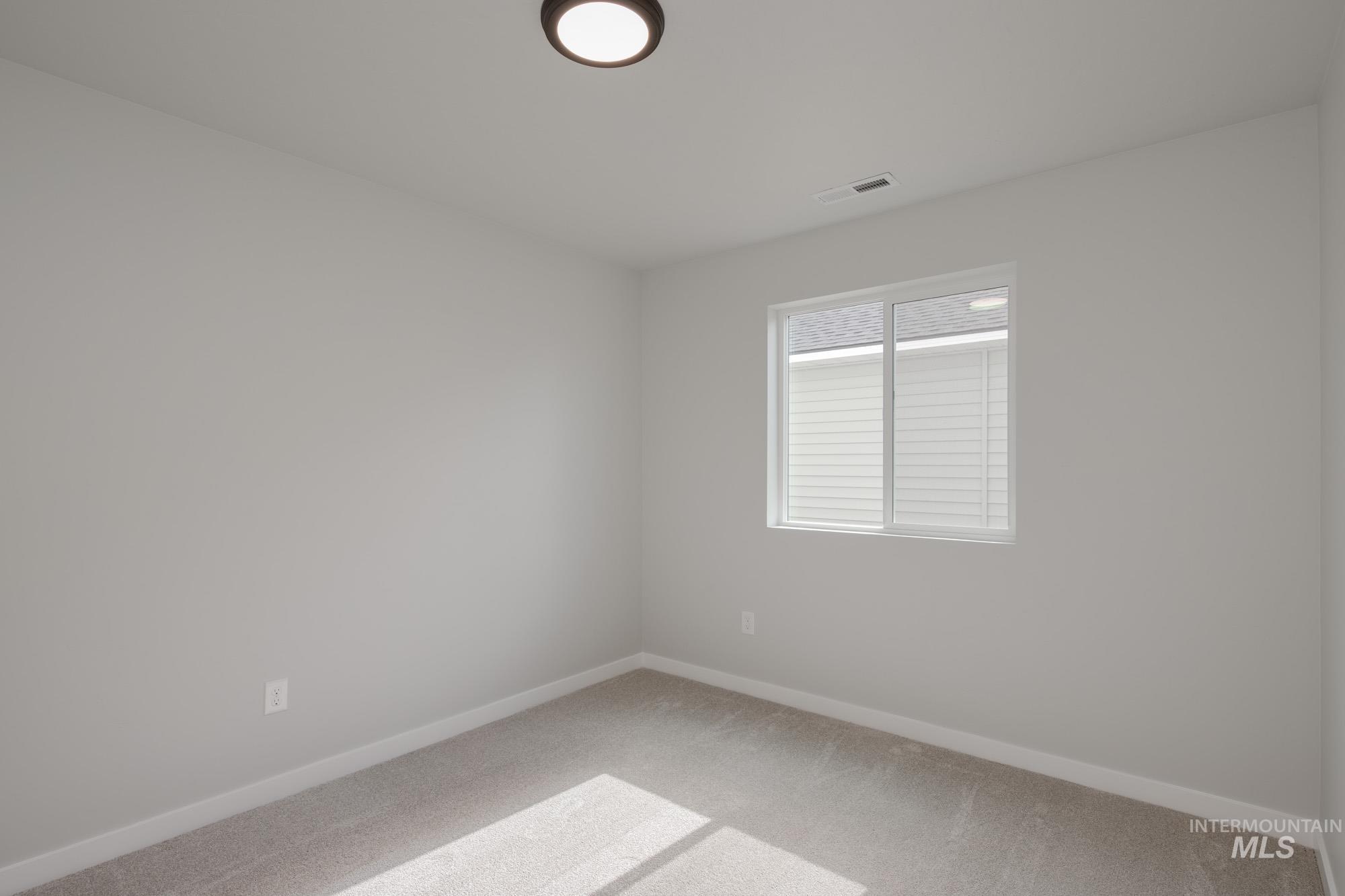 Empty room featuring light colored carpet and baseboards
