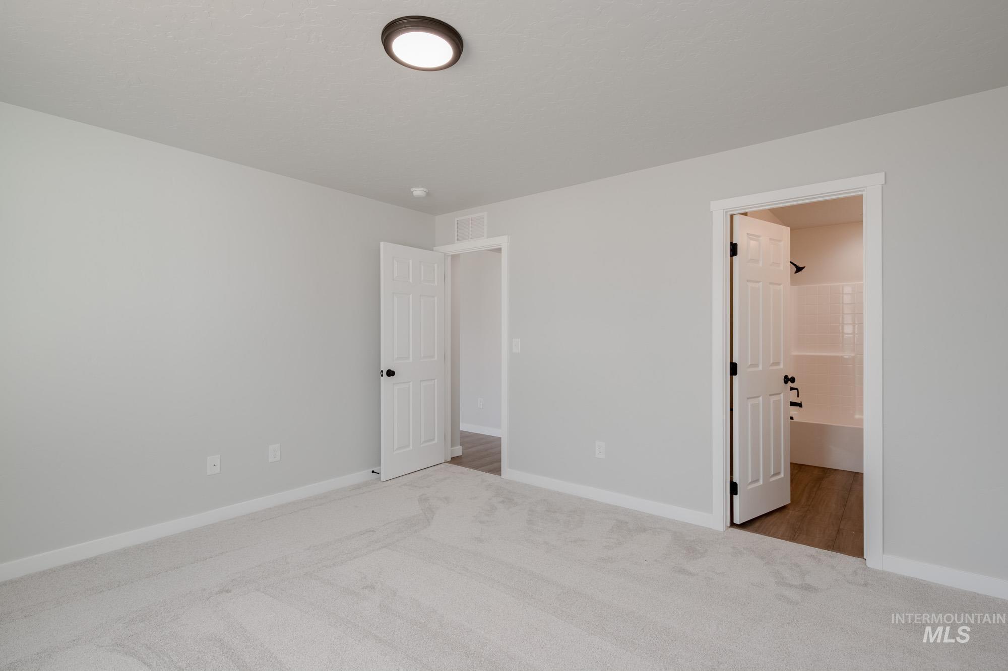 Unfurnished bedroom with carpet flooring and ensuite bath