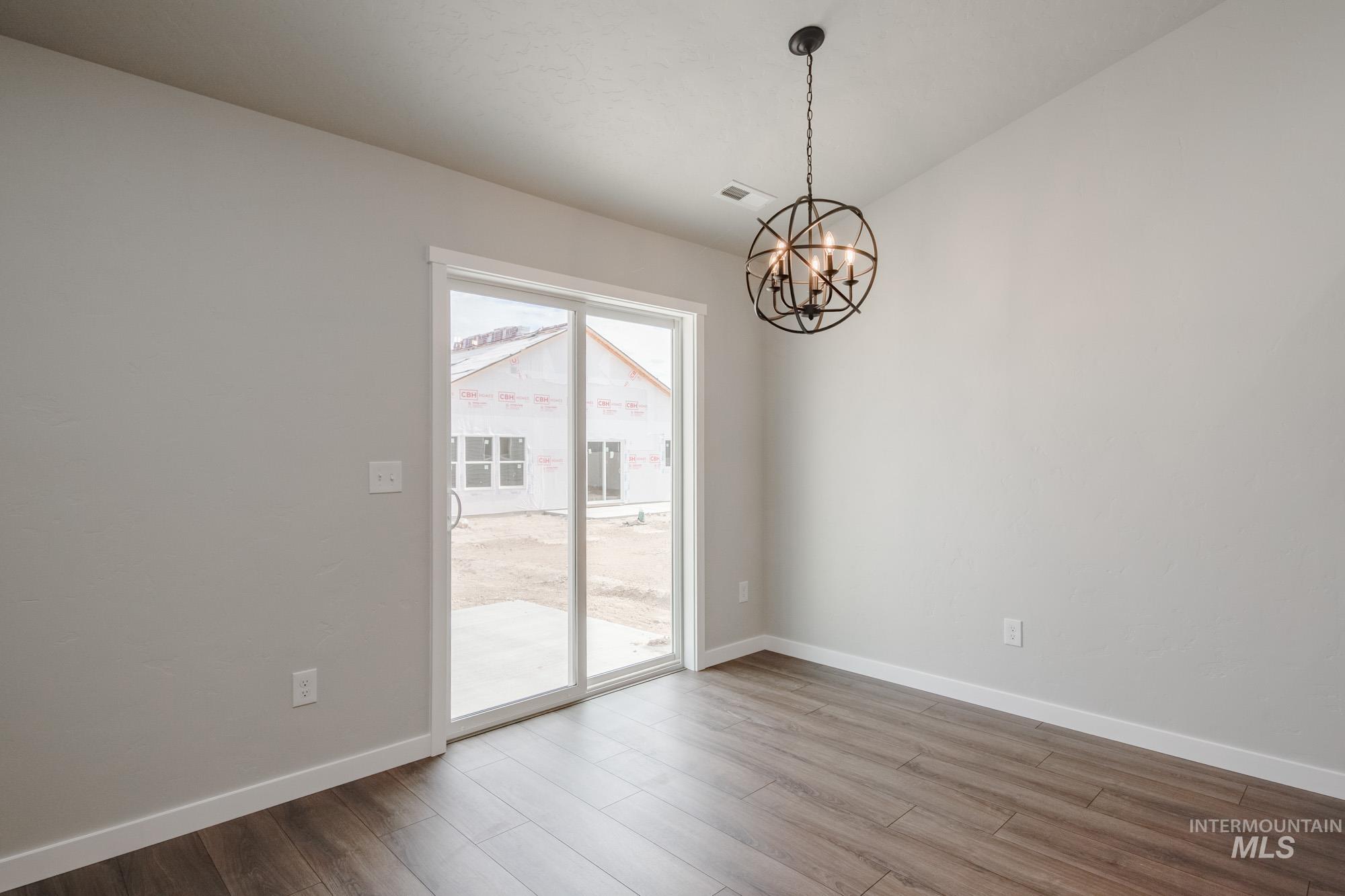 Unfurnished dining area featuring a chandelier and wood finished floors