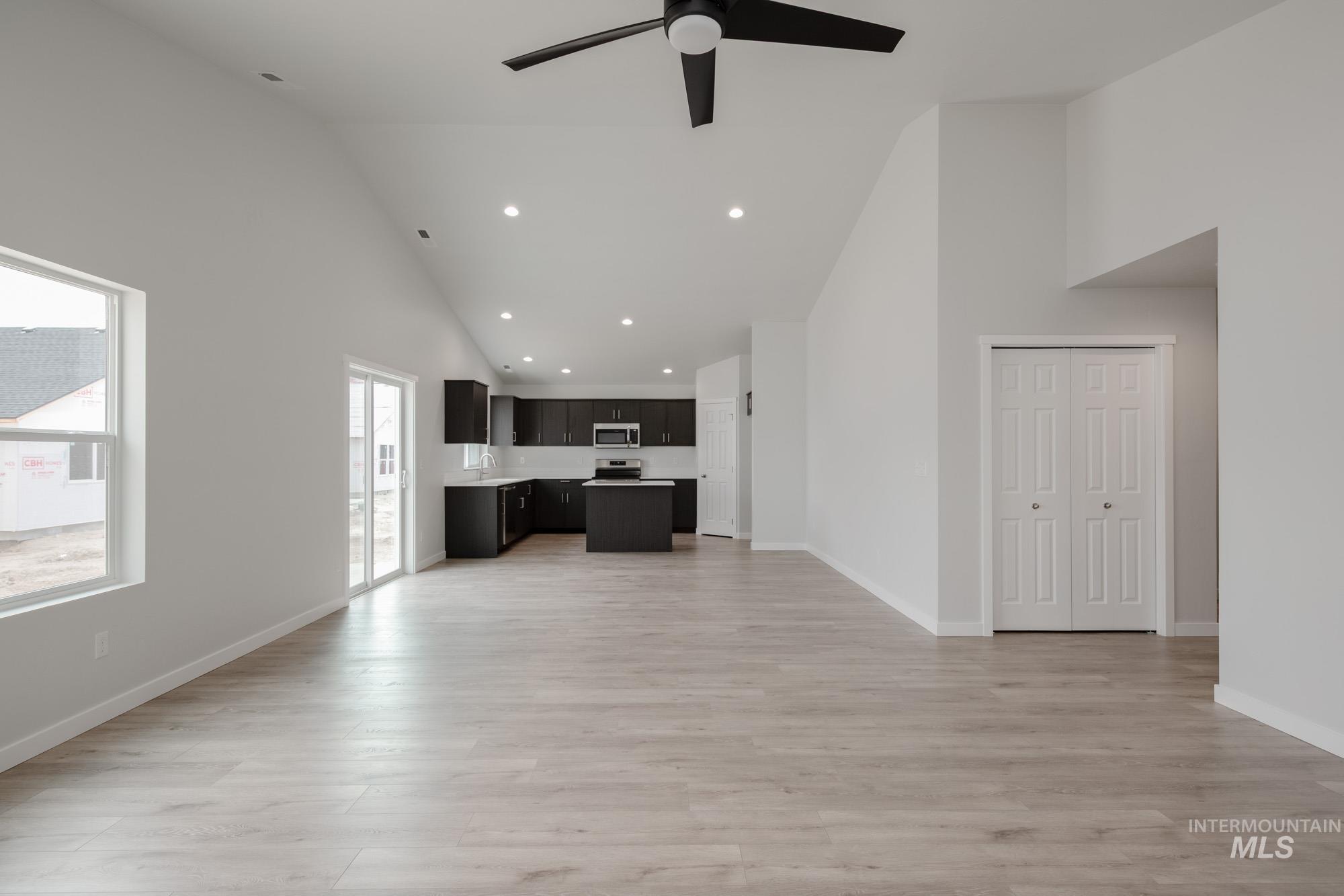 Unfurnished living room featuring high vaulted ceiling, recessed lighting, light wood-style floors, and a ceiling fan