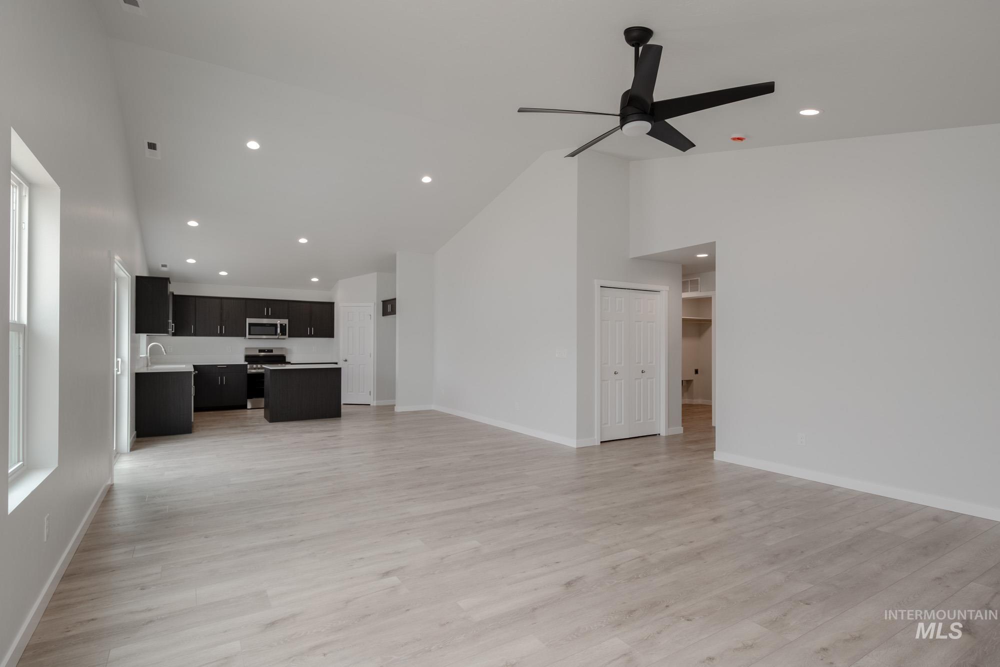 Unfurnished living room with high vaulted ceiling, light wood-style floors, and recessed lighting
