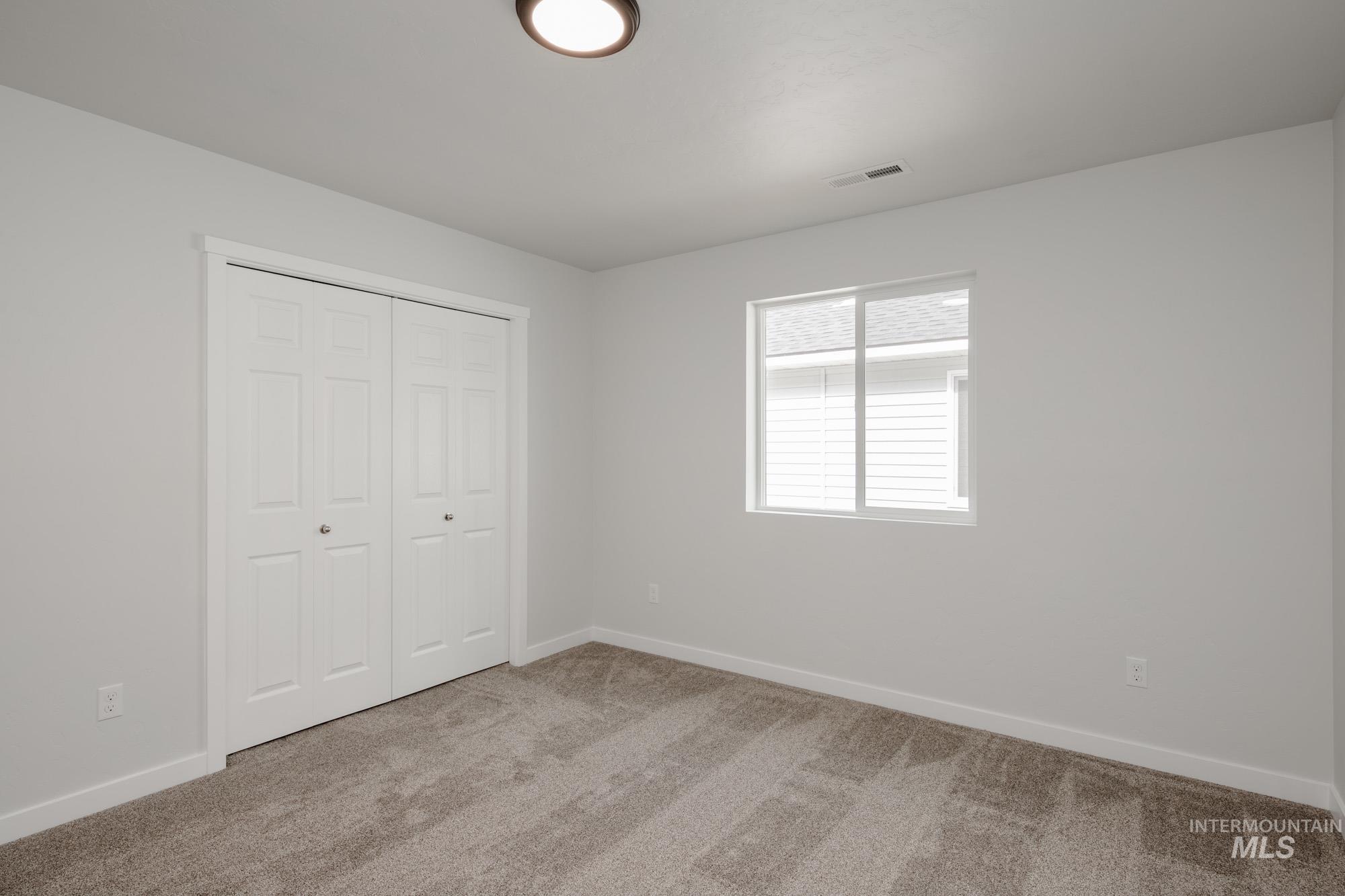 Unfurnished bedroom with light carpet and a closet