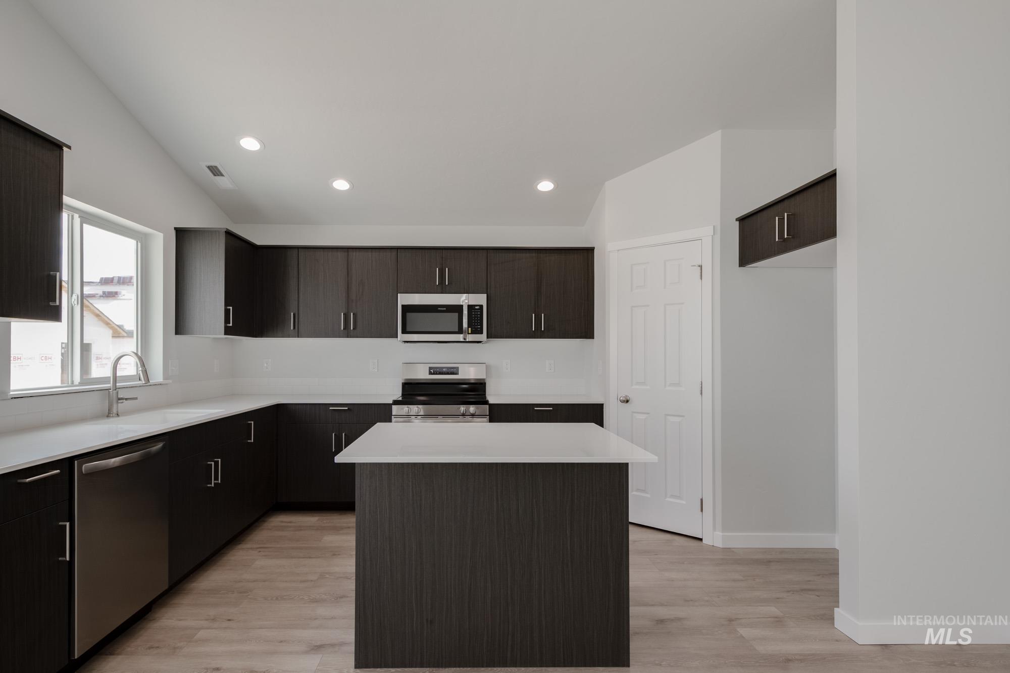 Kitchen with a kitchen island, appliances with stainless steel finishes, recessed lighting, light wood-style floors, and dark brown cabinets