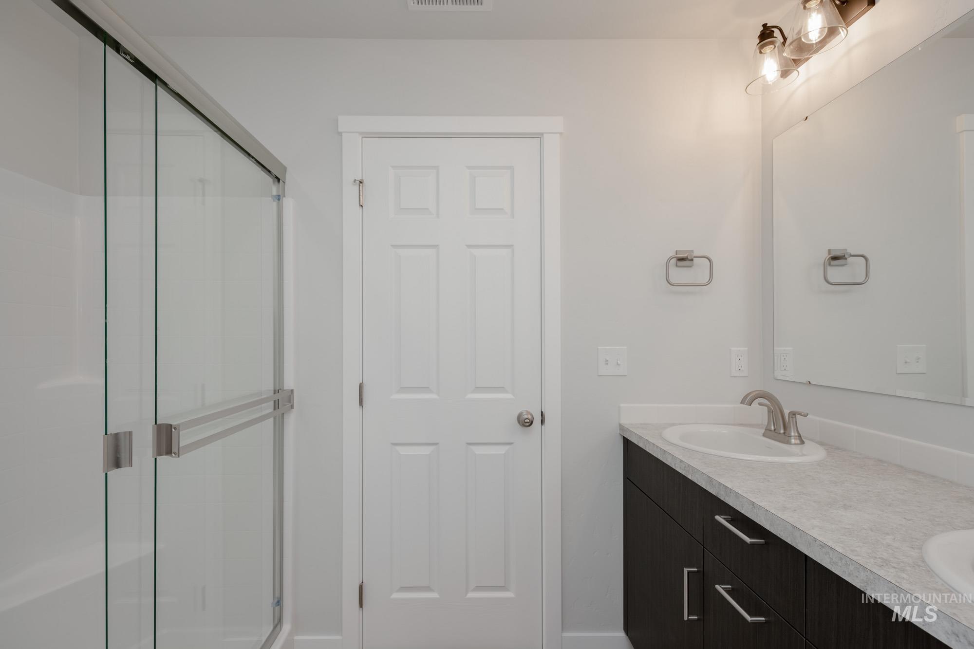 Full bathroom featuring double vanity and a stall shower