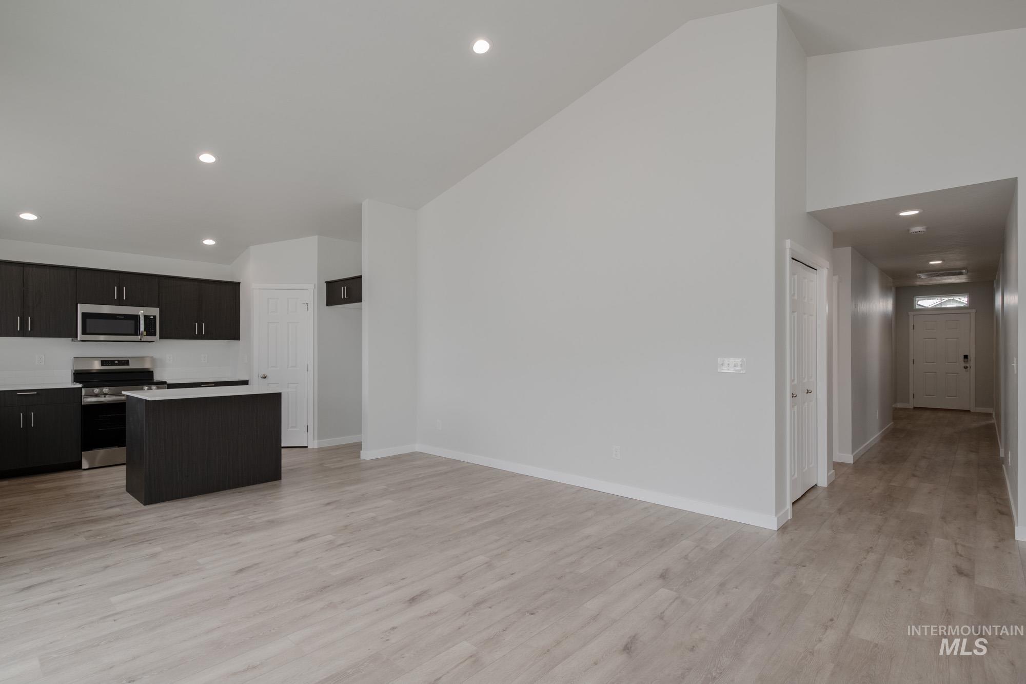 Kitchen featuring recessed lighting, a kitchen island, stainless steel appliances, light wood-type flooring, and light countertops