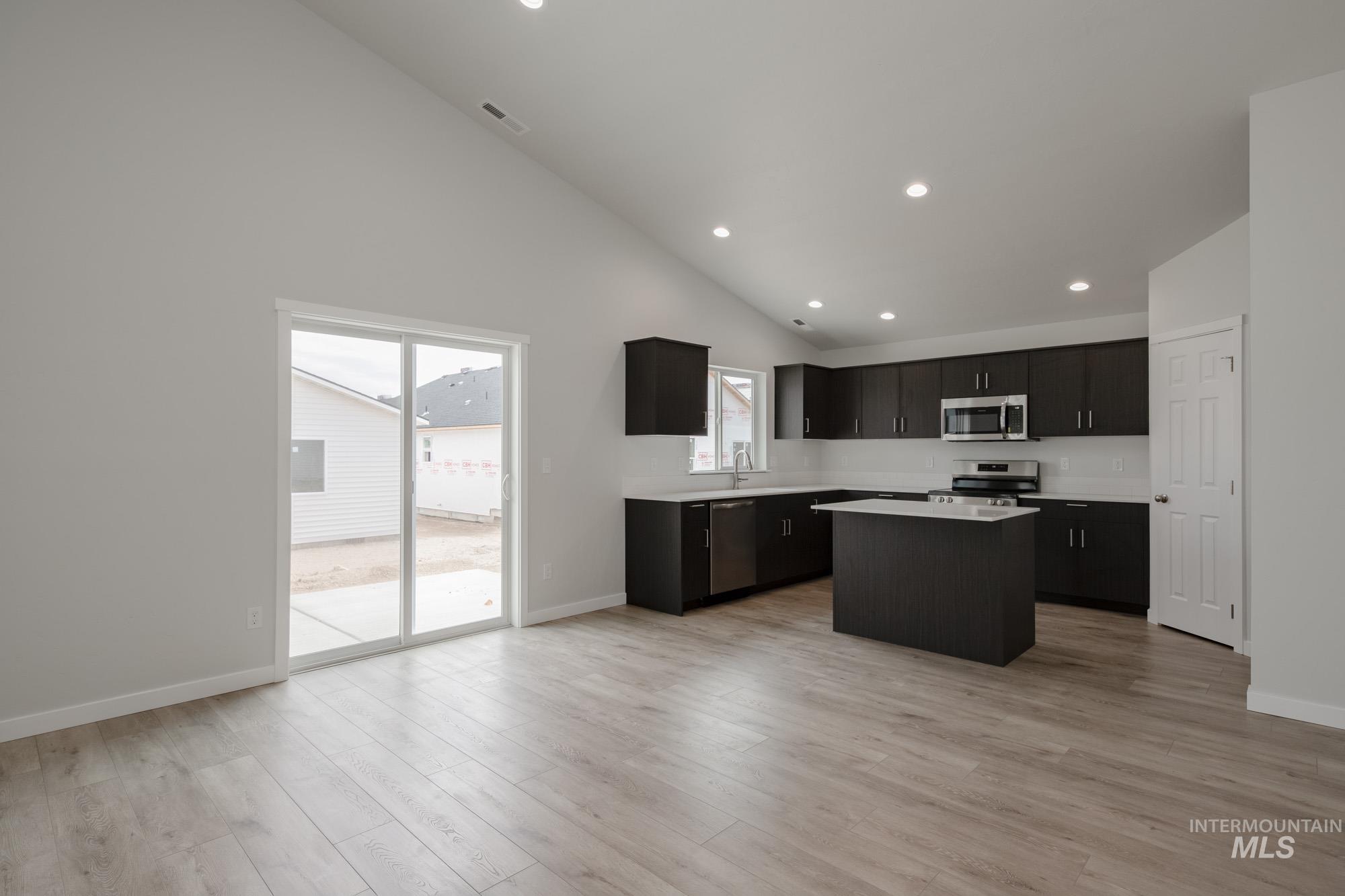 Kitchen with a kitchen island, healthy amount of natural light, recessed lighting, light wood finished floors, and appliances with stainless steel finishes