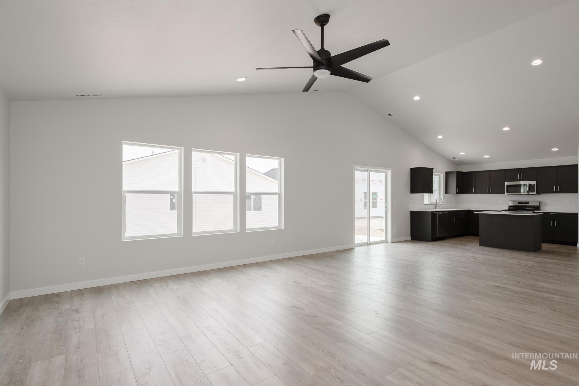 Unfurnished living room with light wood-style flooring, high vaulted ceiling, recessed lighting, and a ceiling fan