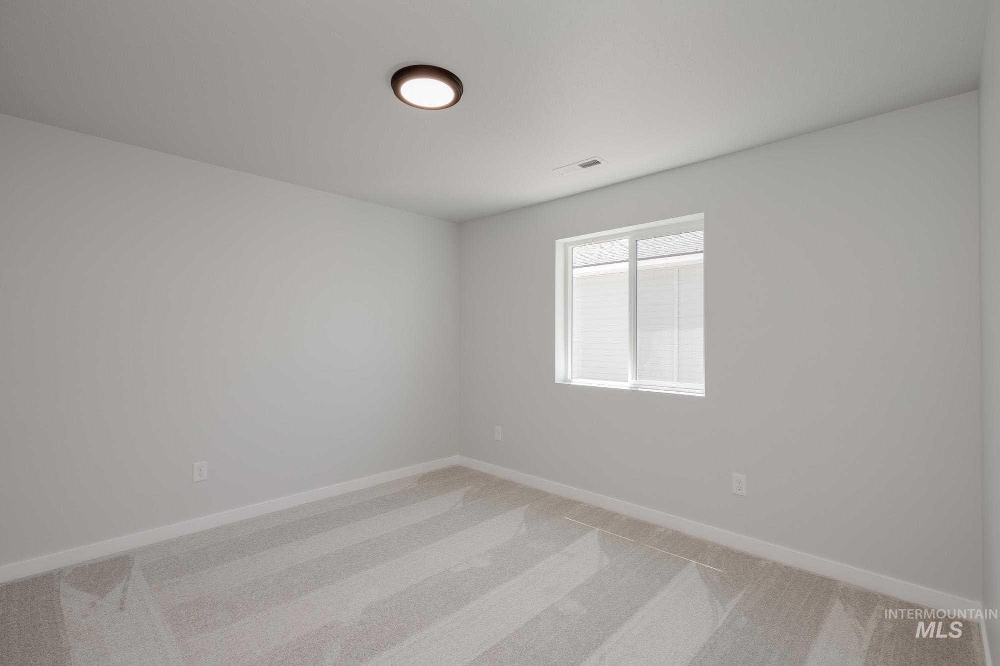Empty room with light colored carpet and baseboards