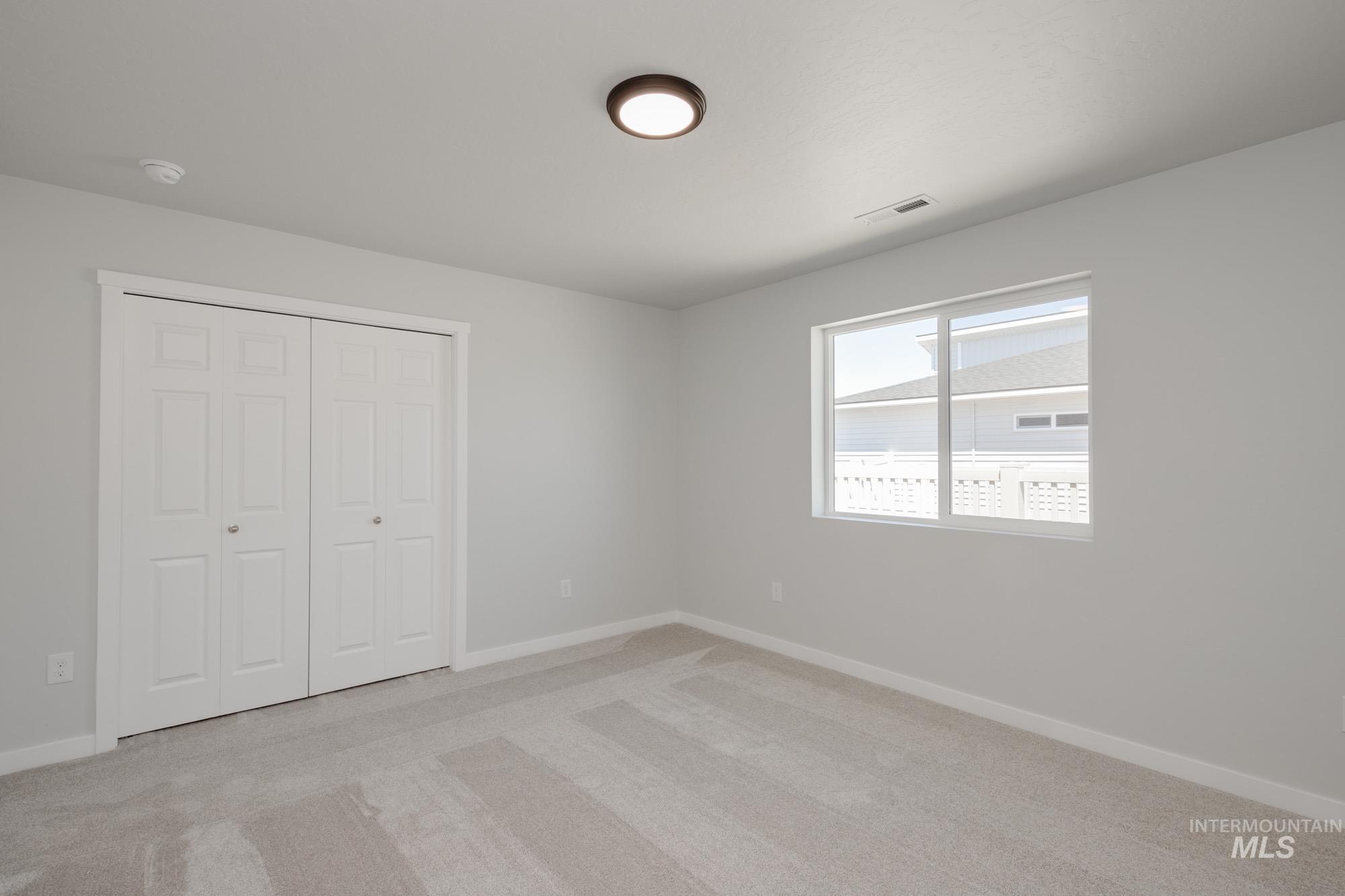 Unfurnished bedroom with light carpet and a closet